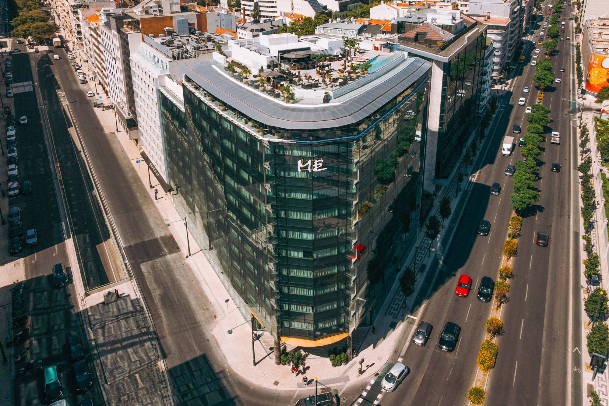 ME Lisbon hotel: modern glass building with rooftop pool, urban street view.