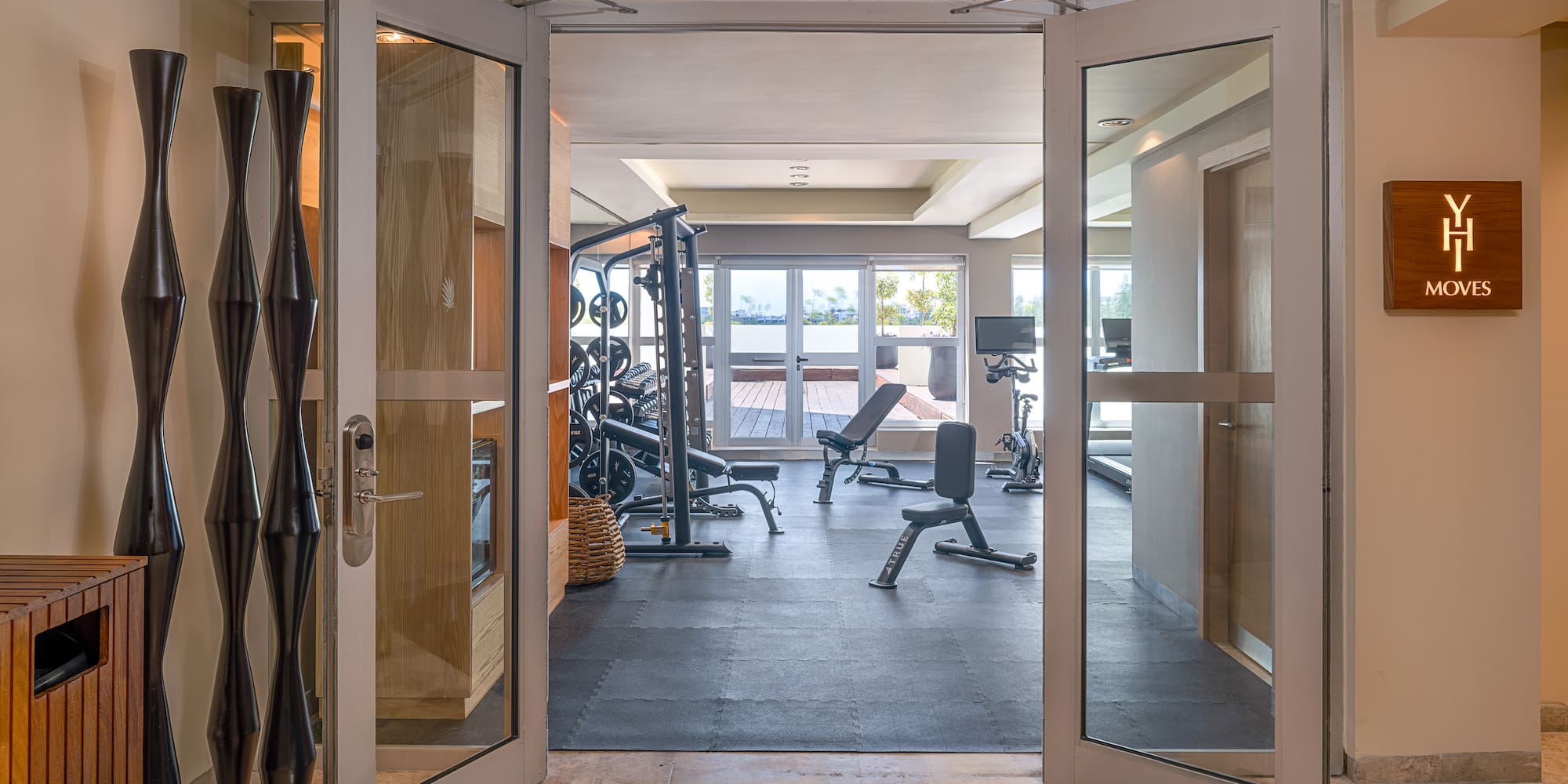 Hotel gym with YH Moves sign, exercise equipment, and outdoor deck.