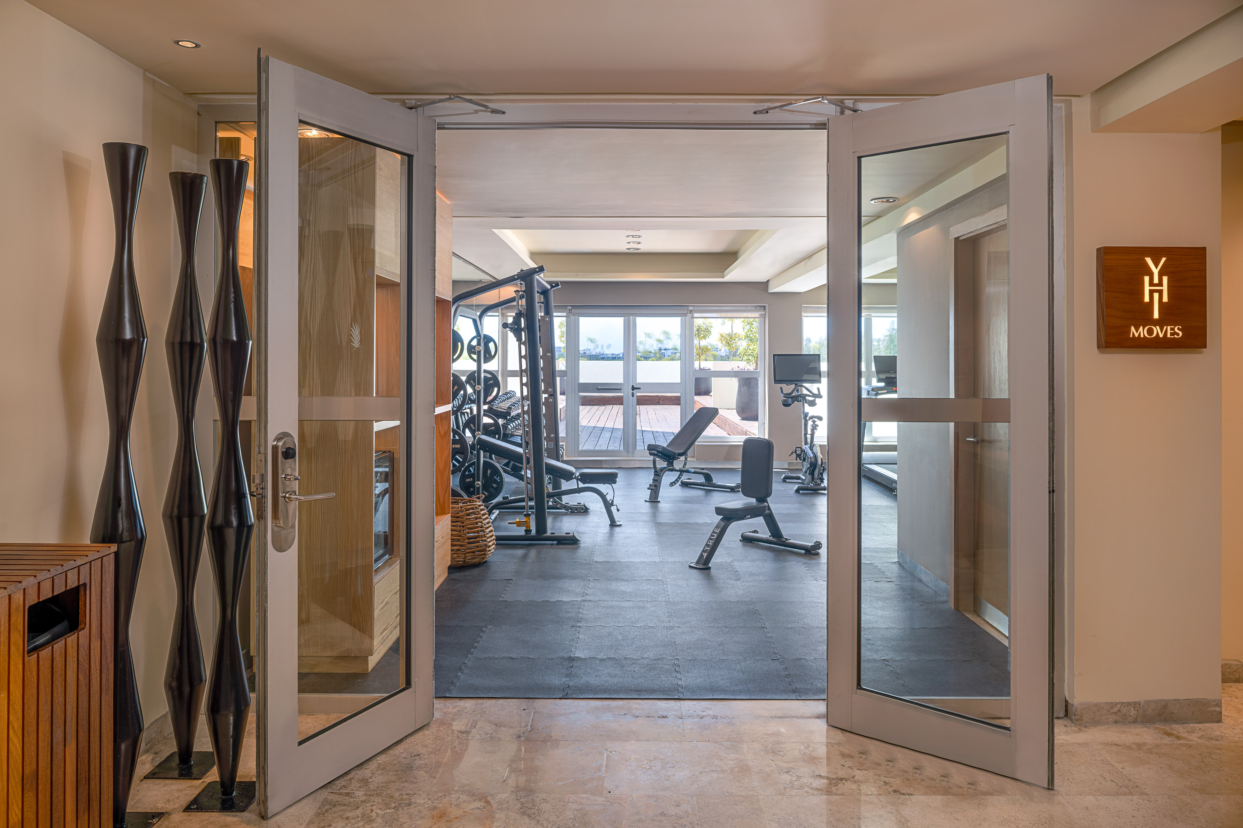 Hotel gym with YH Moves sign, exercise equipment, and outdoor deck.