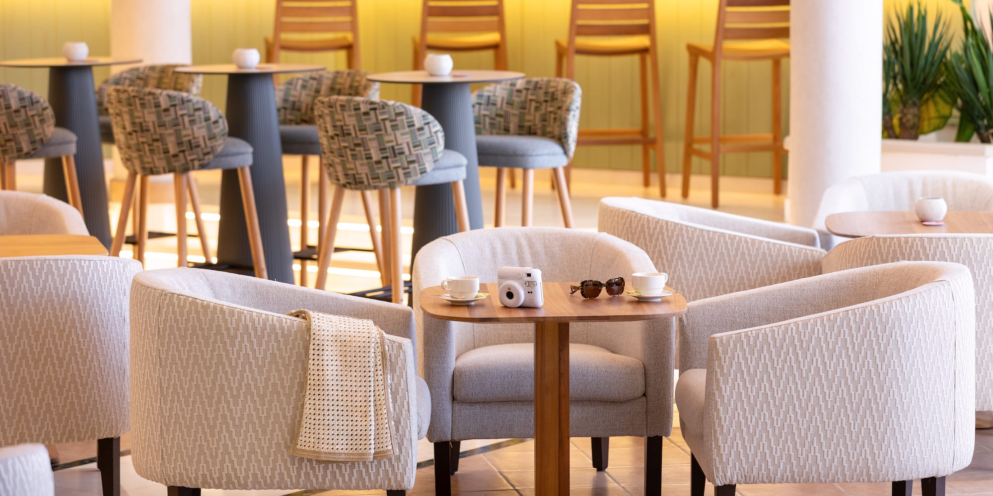 Hotel lounge seating with armchairs, coffee tables, and illuminated bar.