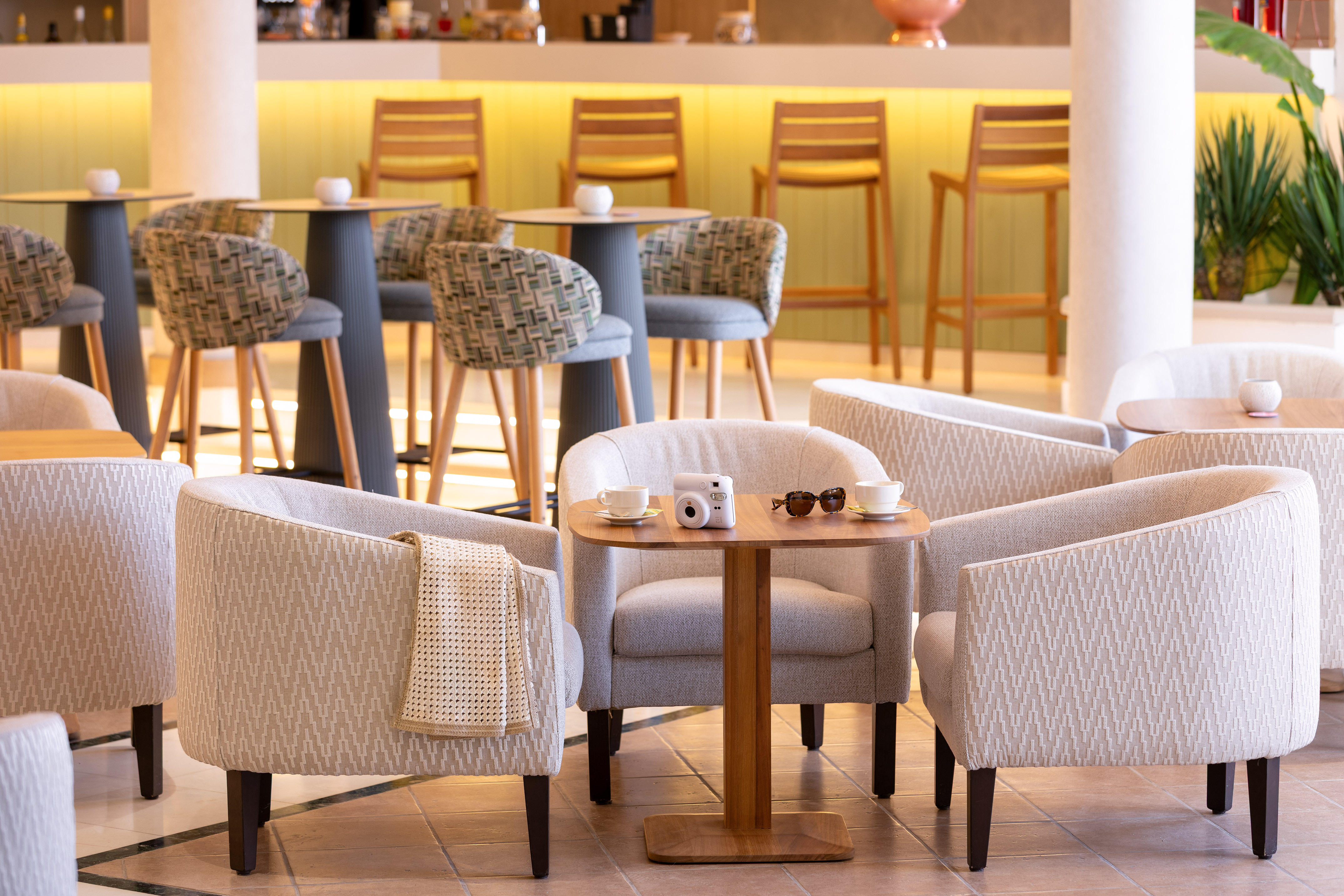 Hotel lounge seating with armchairs, coffee tables, and illuminated bar.