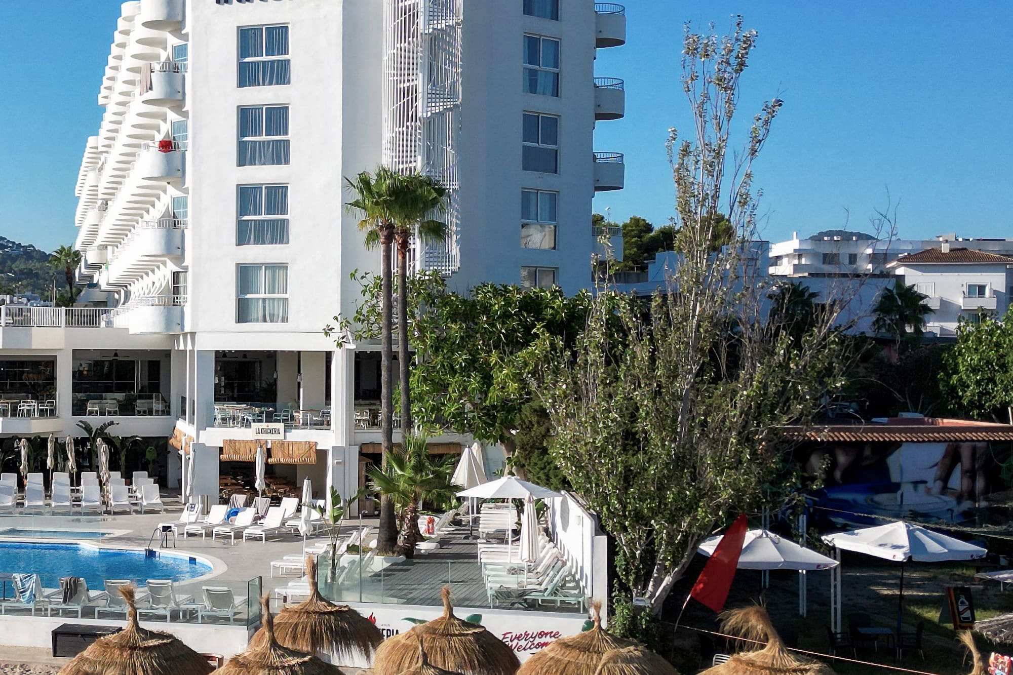 INNSiDE hotel, sandy beach with straw umbrellas, and swimming pool.