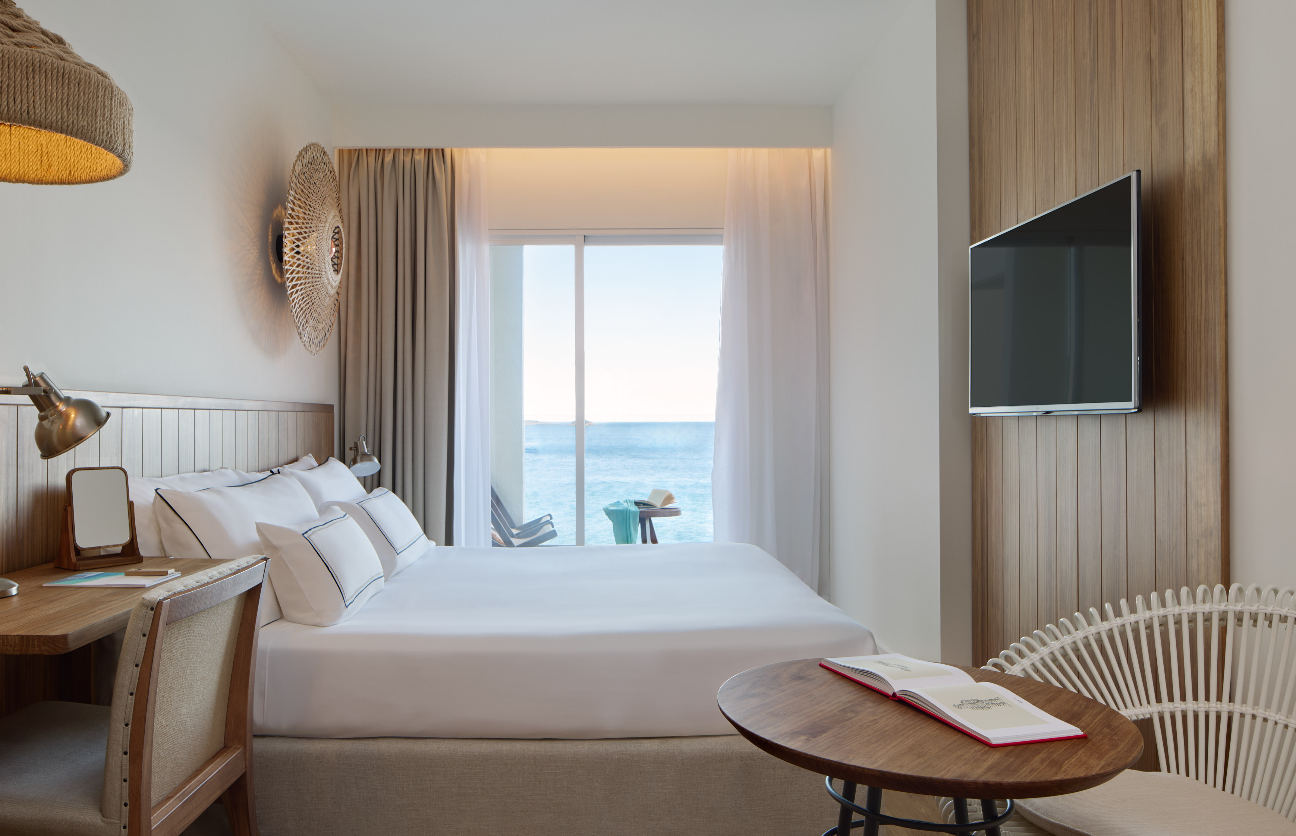 Ocean view hotel room with large bed, modern furnishings, and balcony.