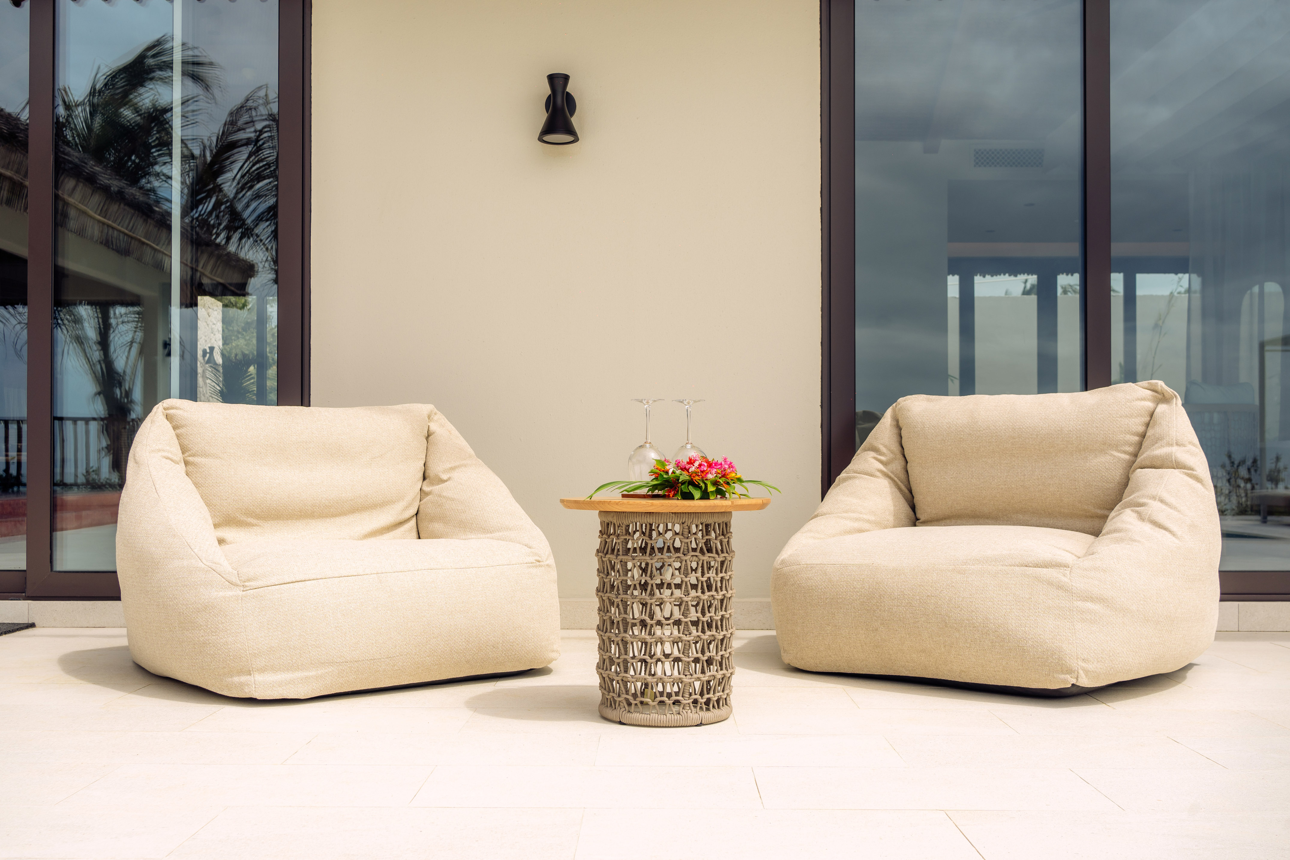 Beige outdoor bean bag chairs and woven table on a modern patio.