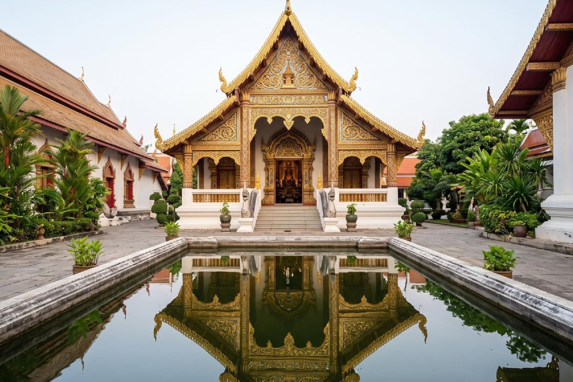 Ornate golden Thai temple reflected in tranquil pool.