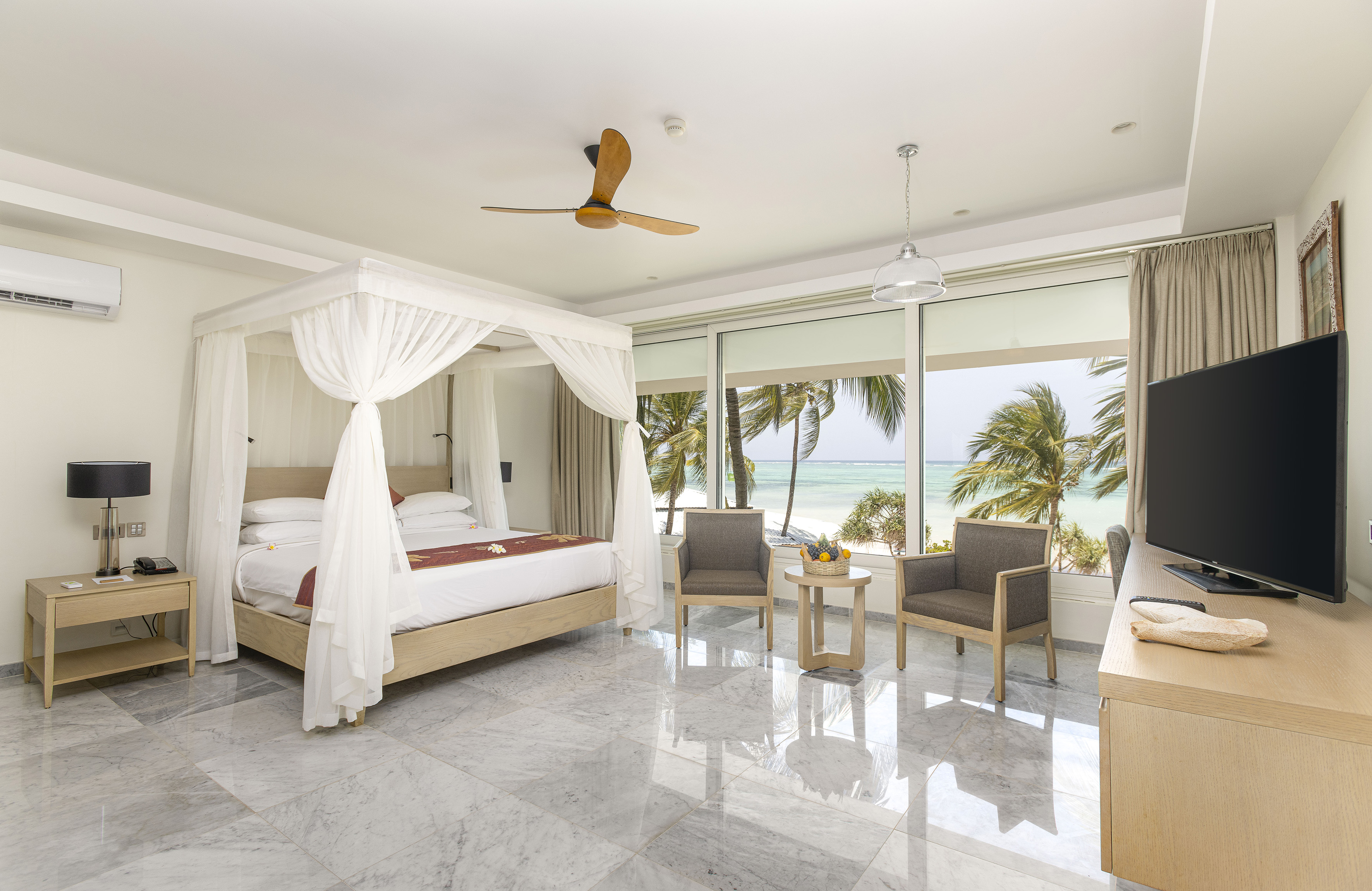 a room with a bed and chairs and a ceiling fan