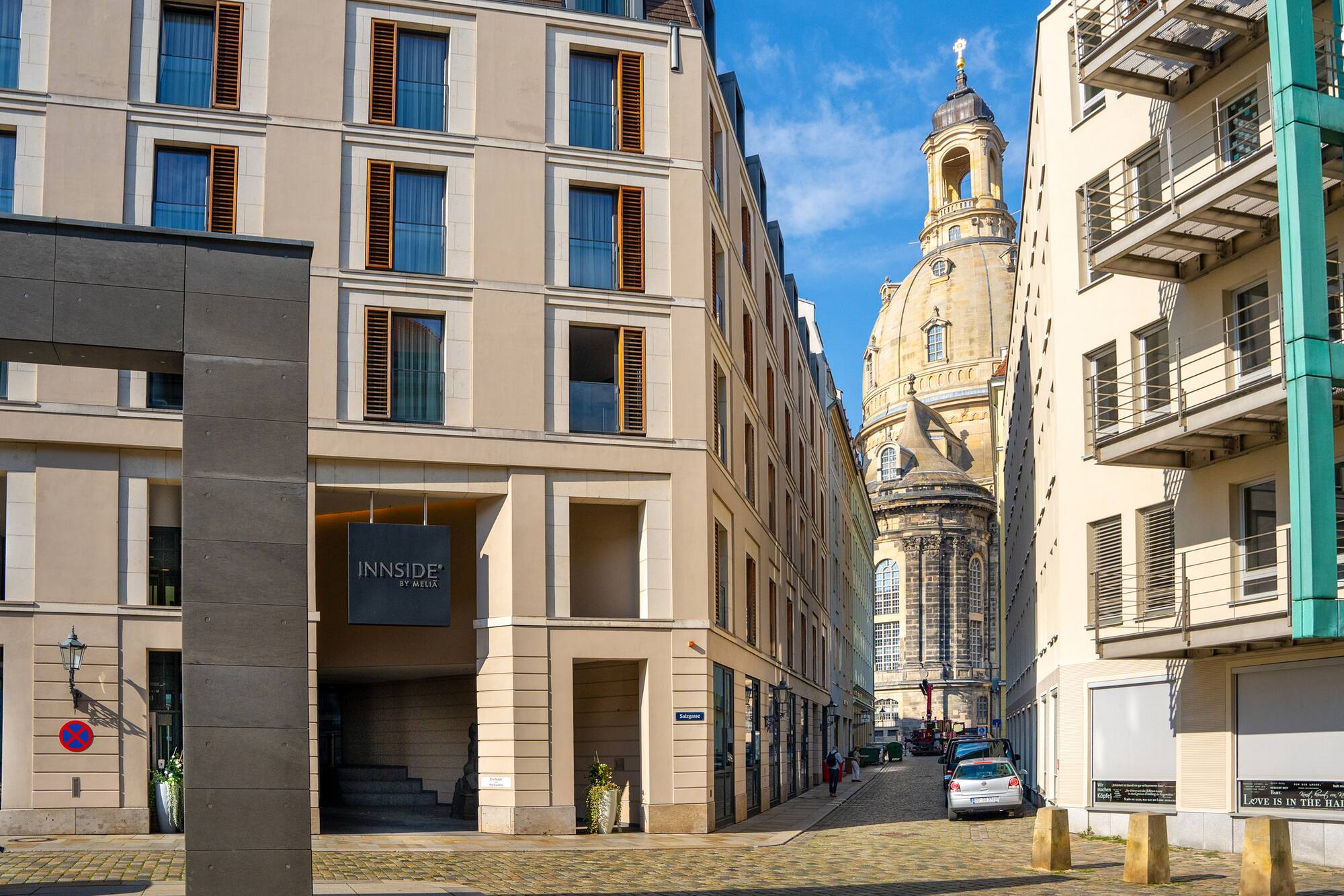 Dresden street with INNSIDE hotel and Frauenkirche against blue sky.