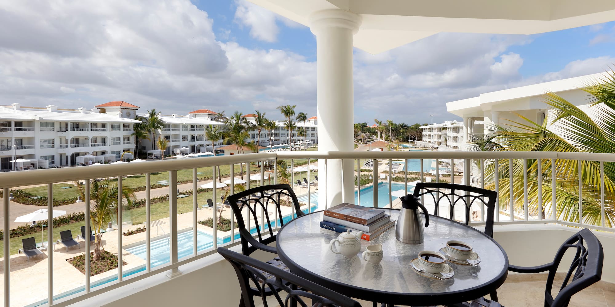 a table and chairs on a balcony with a pool in the background