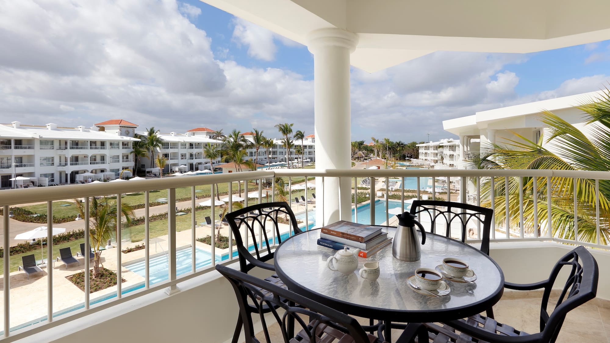 a table and chairs on a balcony with a pool in the background