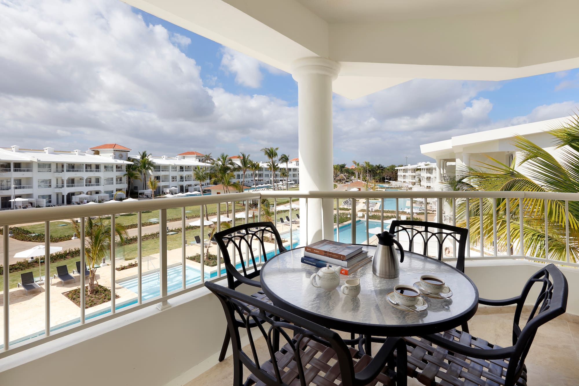 a table and chairs on a balcony with a pool in the background