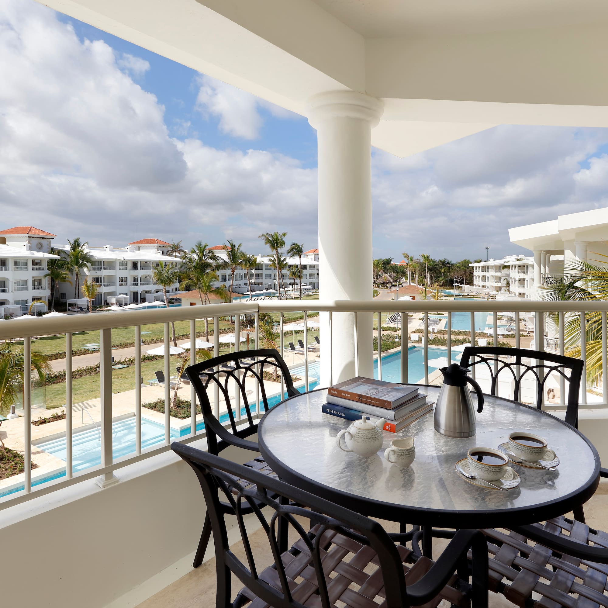 a table and chairs on a balcony with a pool in the background