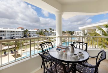 a table and chairs on a balcony with a pool in the background