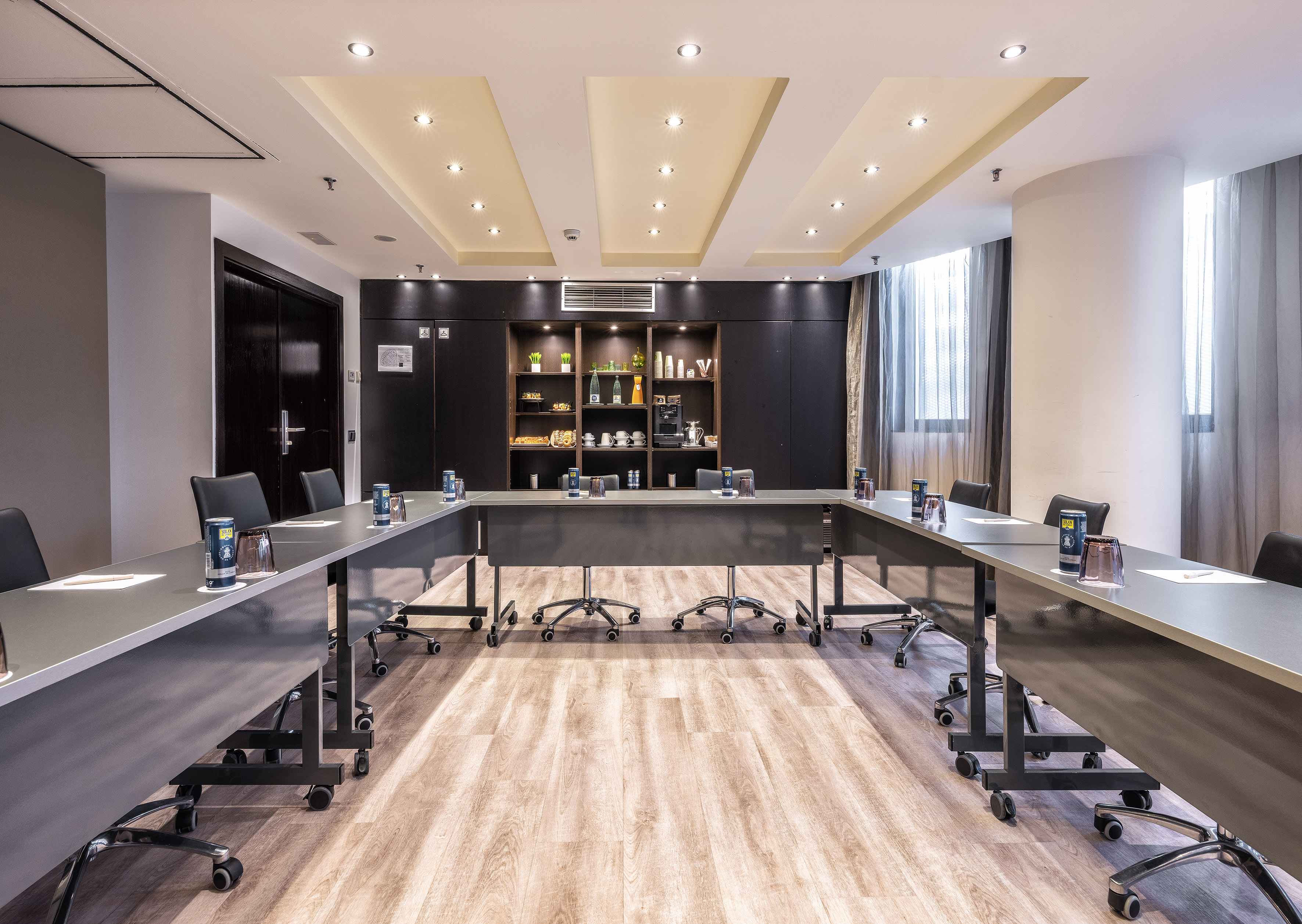 Modern U-shaped conference room with dark tables, chairs, wood floor, and snack bar. - MAR BELLA - فندق برشلونة كوندال مار(Condal Mar) المنتسب لـ Melia, برشلونة