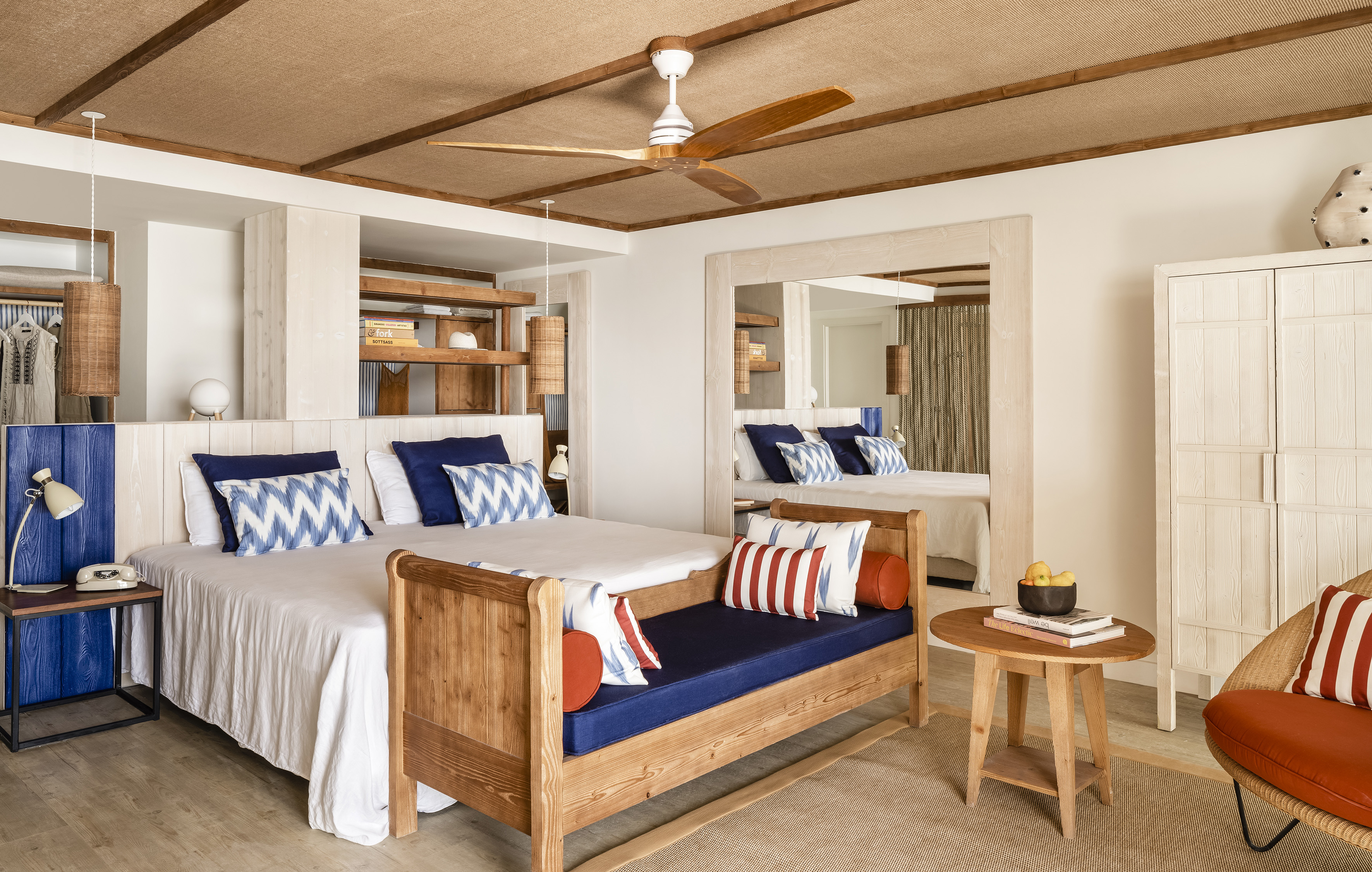 Bright resort bedroom with wooden ceiling fan, daybed, and blue accents.