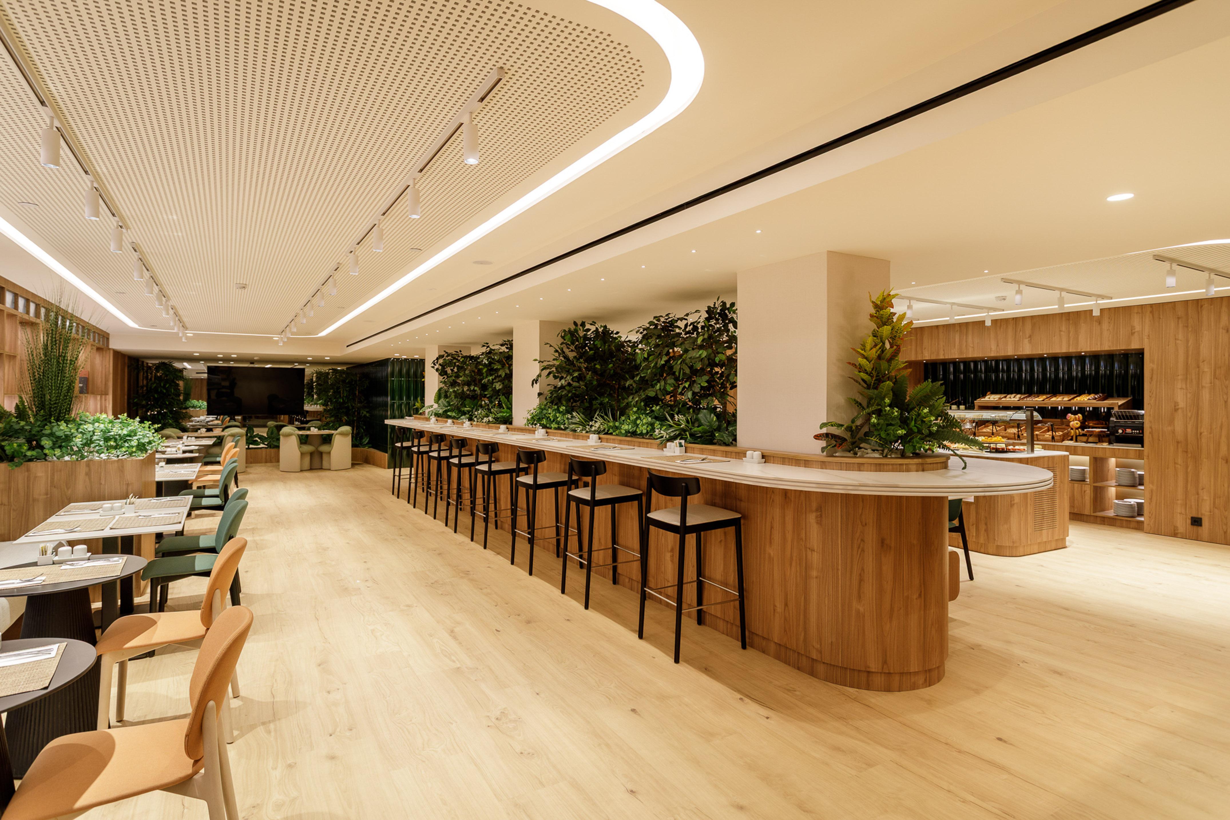 Modern restaurant buffet with long bar, wood, and green plants.