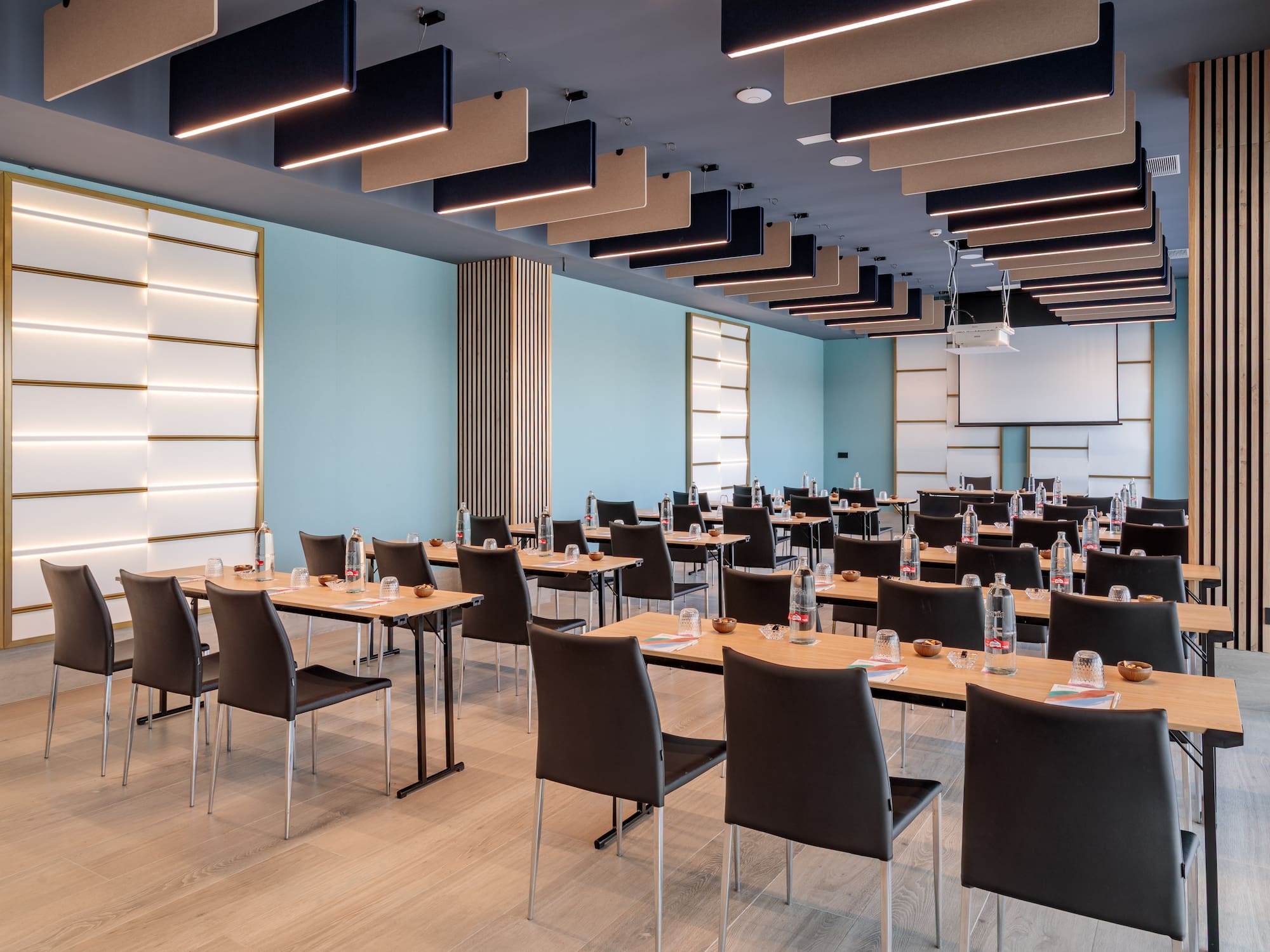 Modern conference room with tables, chairs, projector, and light blue walls.