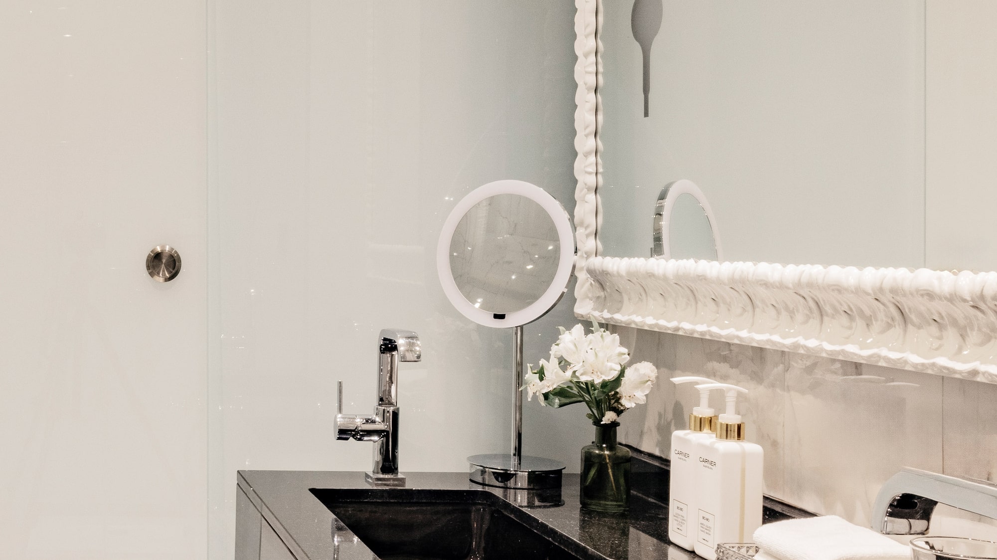 Baño moderno con lavabos dobles negros, espejo y detalles de lujo.
