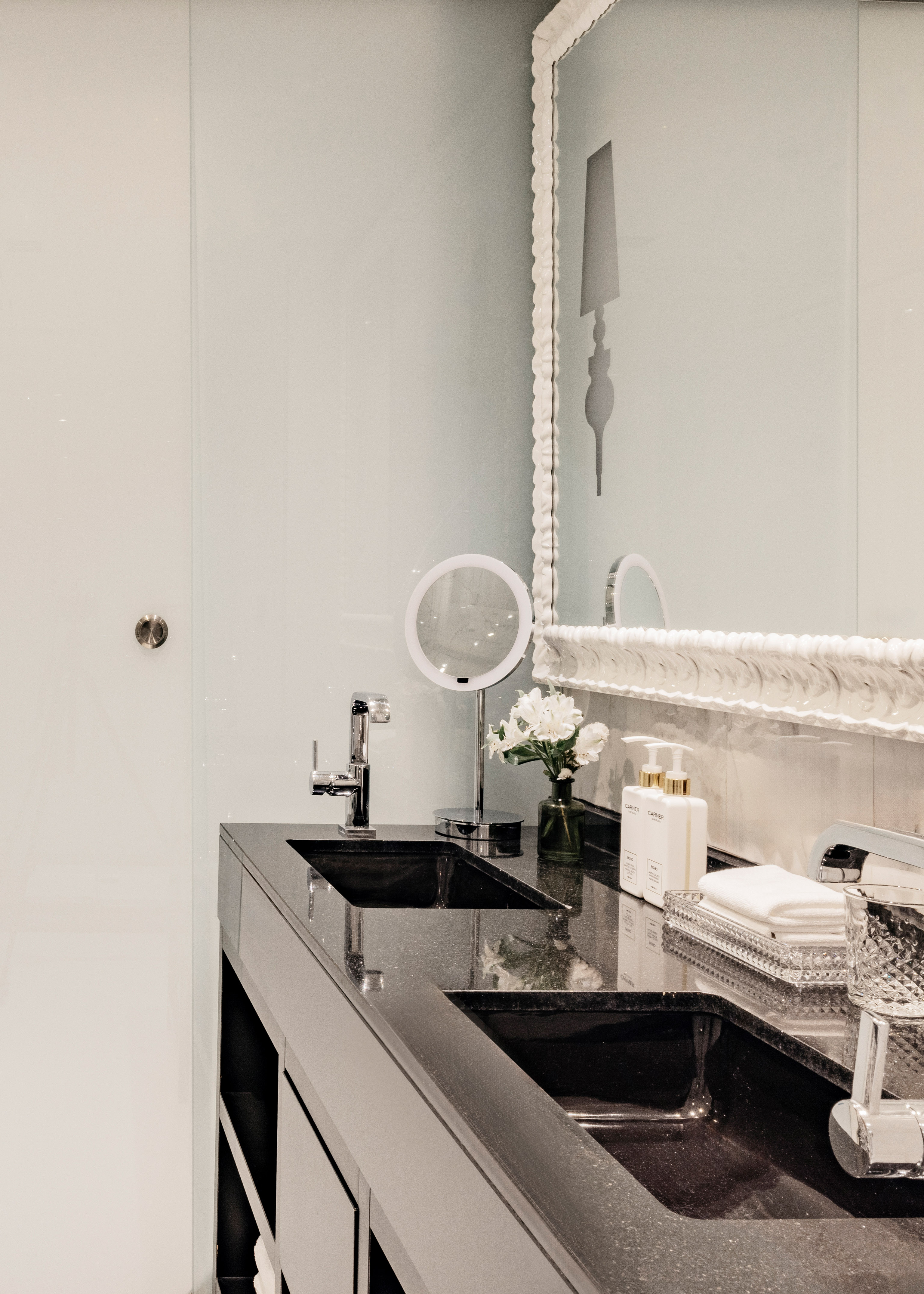 Baño moderno con lavabos dobles negros, espejo y detalles de lujo.
