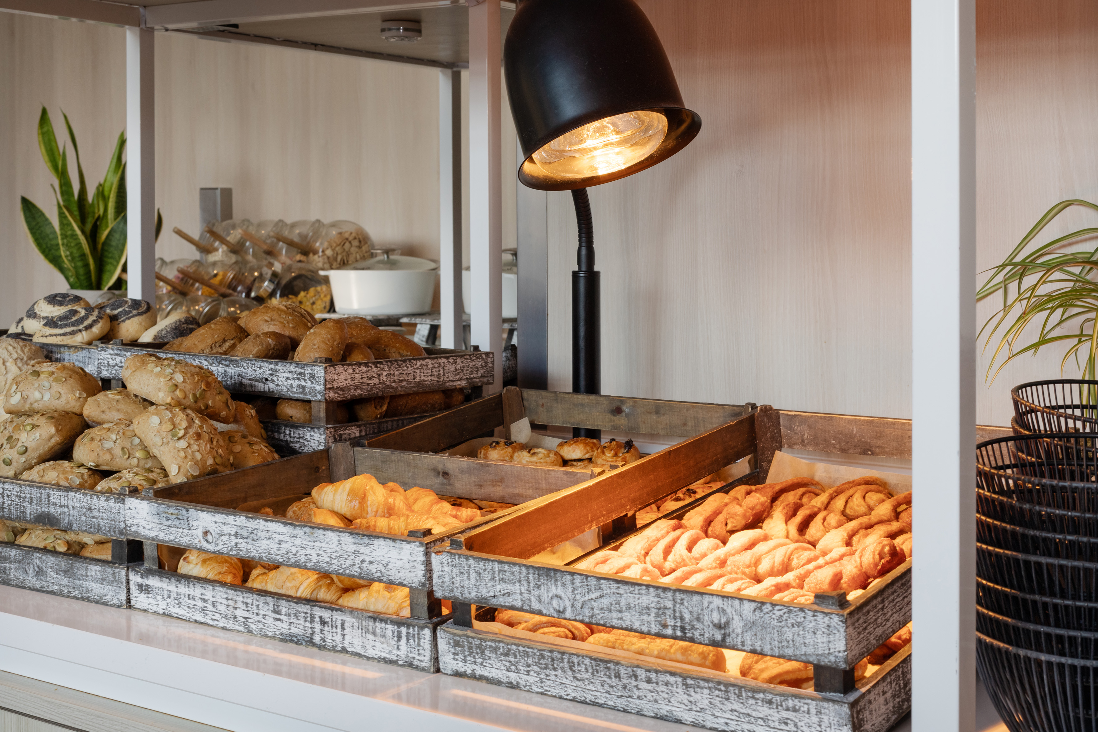 Breakfast buffet display with fresh bread, croissants, and assorted pastries.