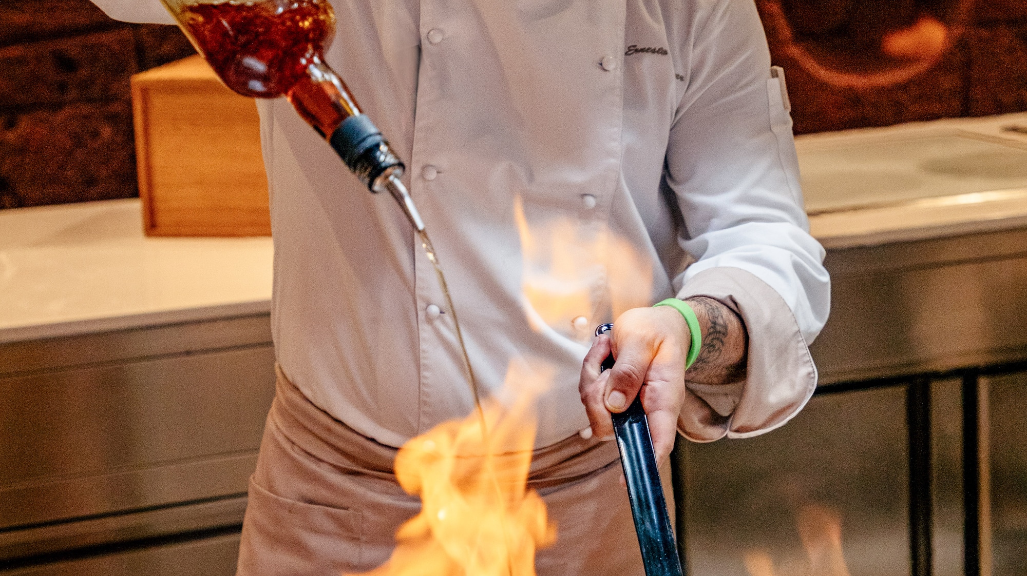 a man pouring a sauce into a pan of food