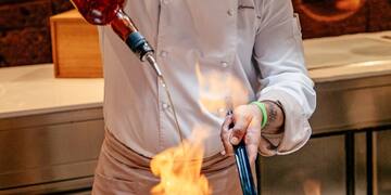 a man pouring a sauce into a pan of food