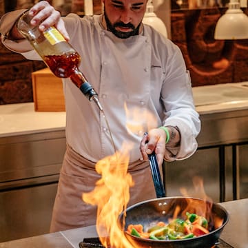 a man pouring a sauce into a pan of food