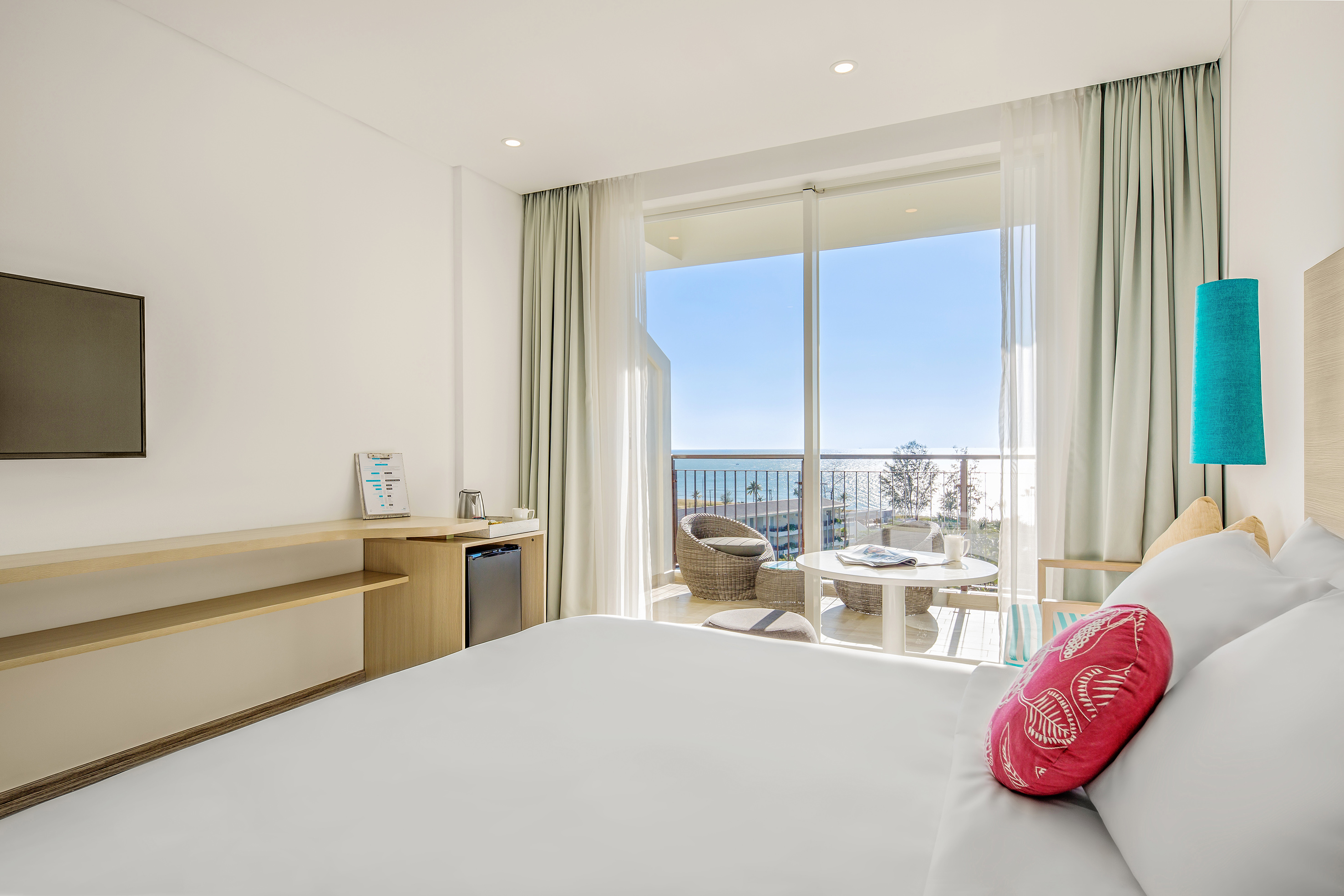 Luxury hotel room with private balcony overlooking the sea and beach.