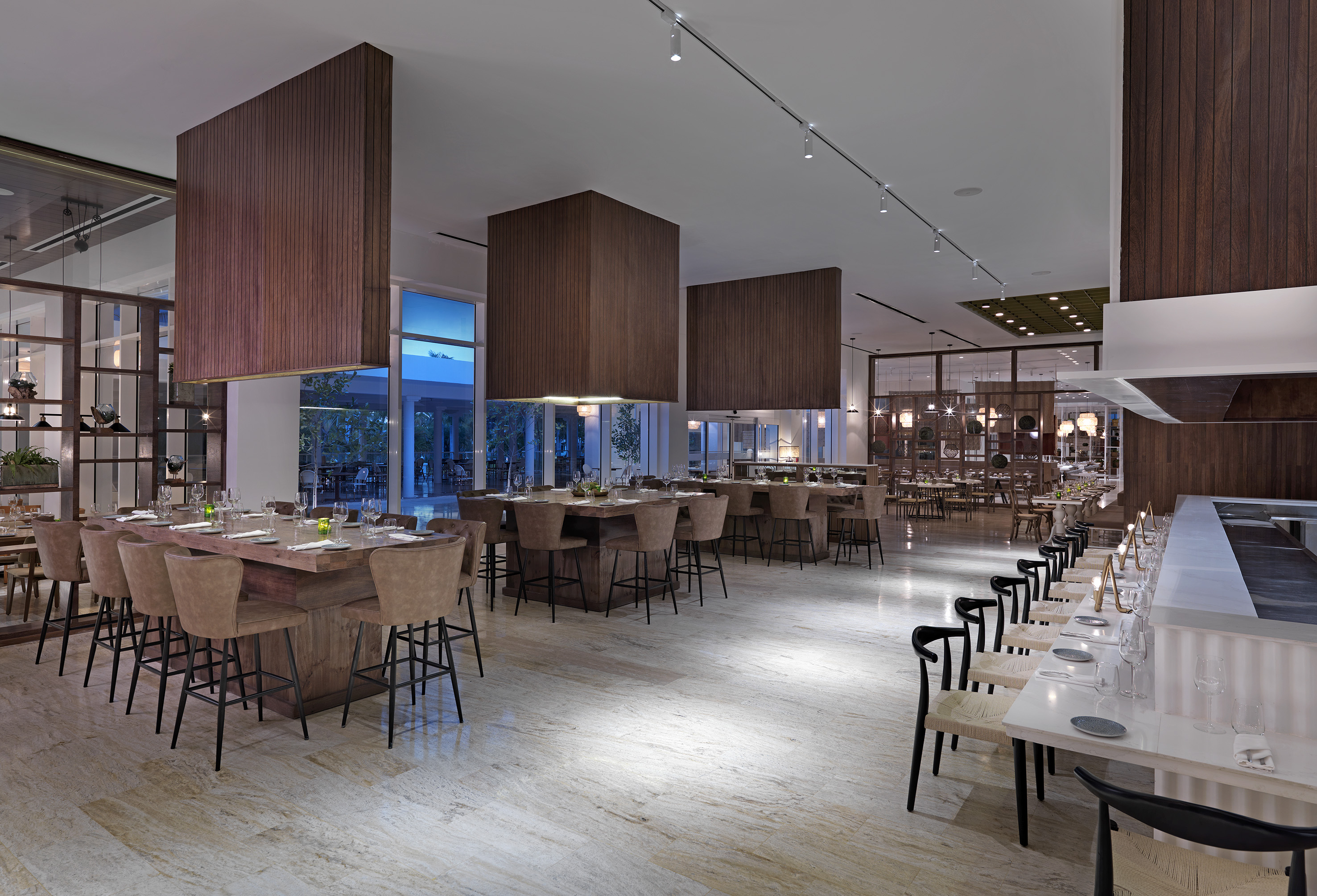 Modern restaurant dining room with wood panels, high tables, and elegant settings.
