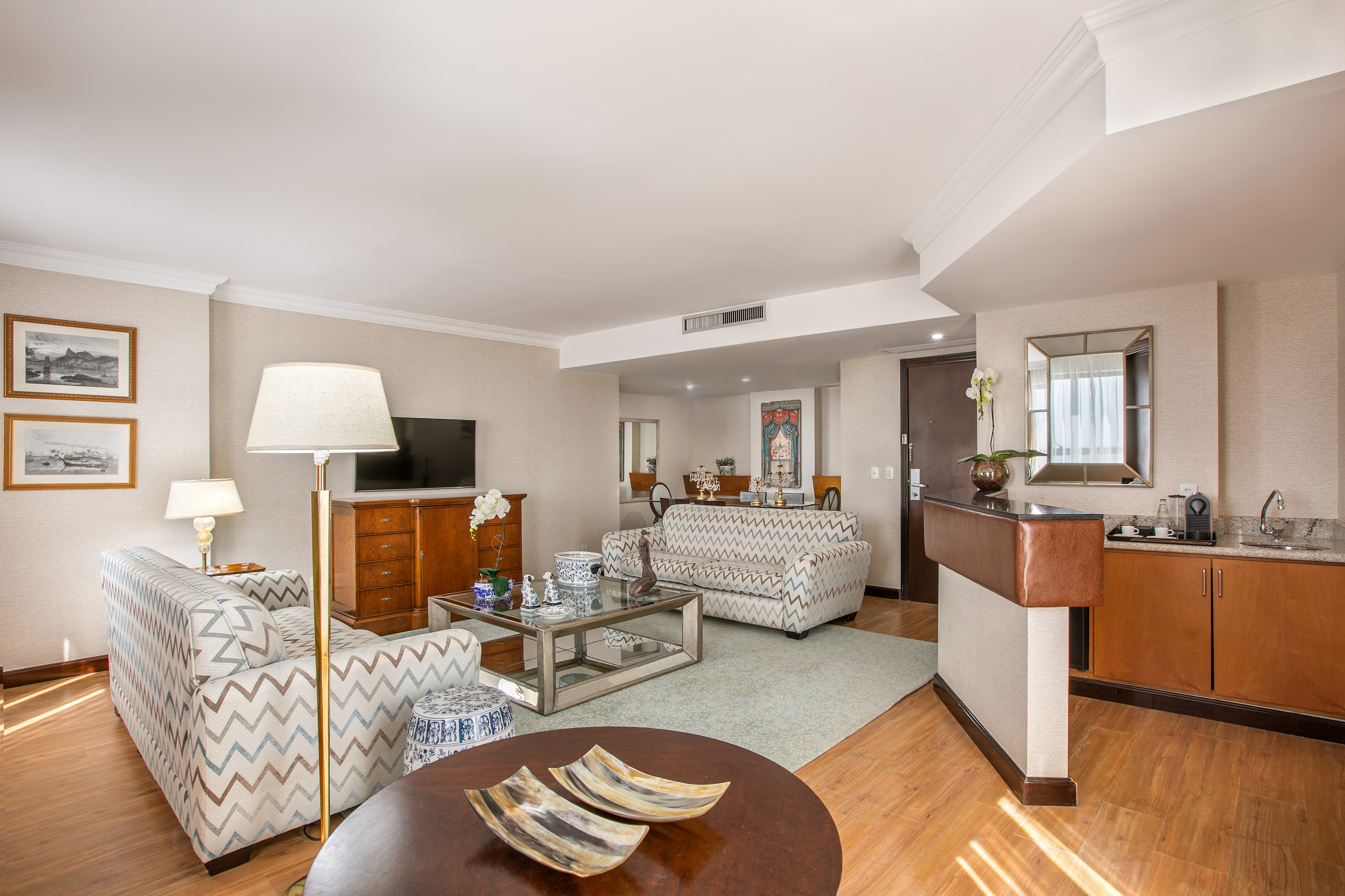Luxury hotel suite living room with chevron sofas and wet bar.