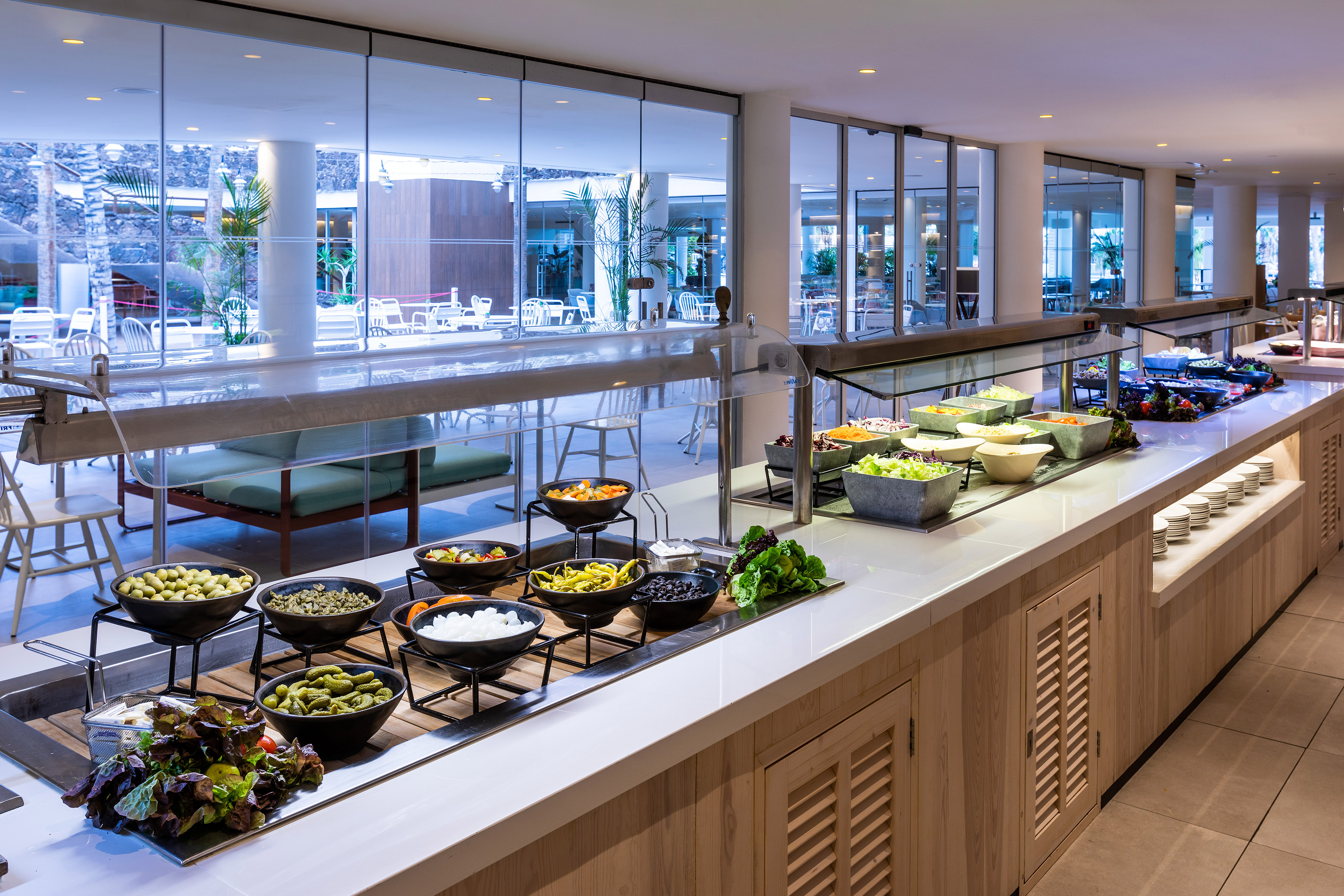Hotel buffet salad bar with fresh vegetables, olives, and toppings.