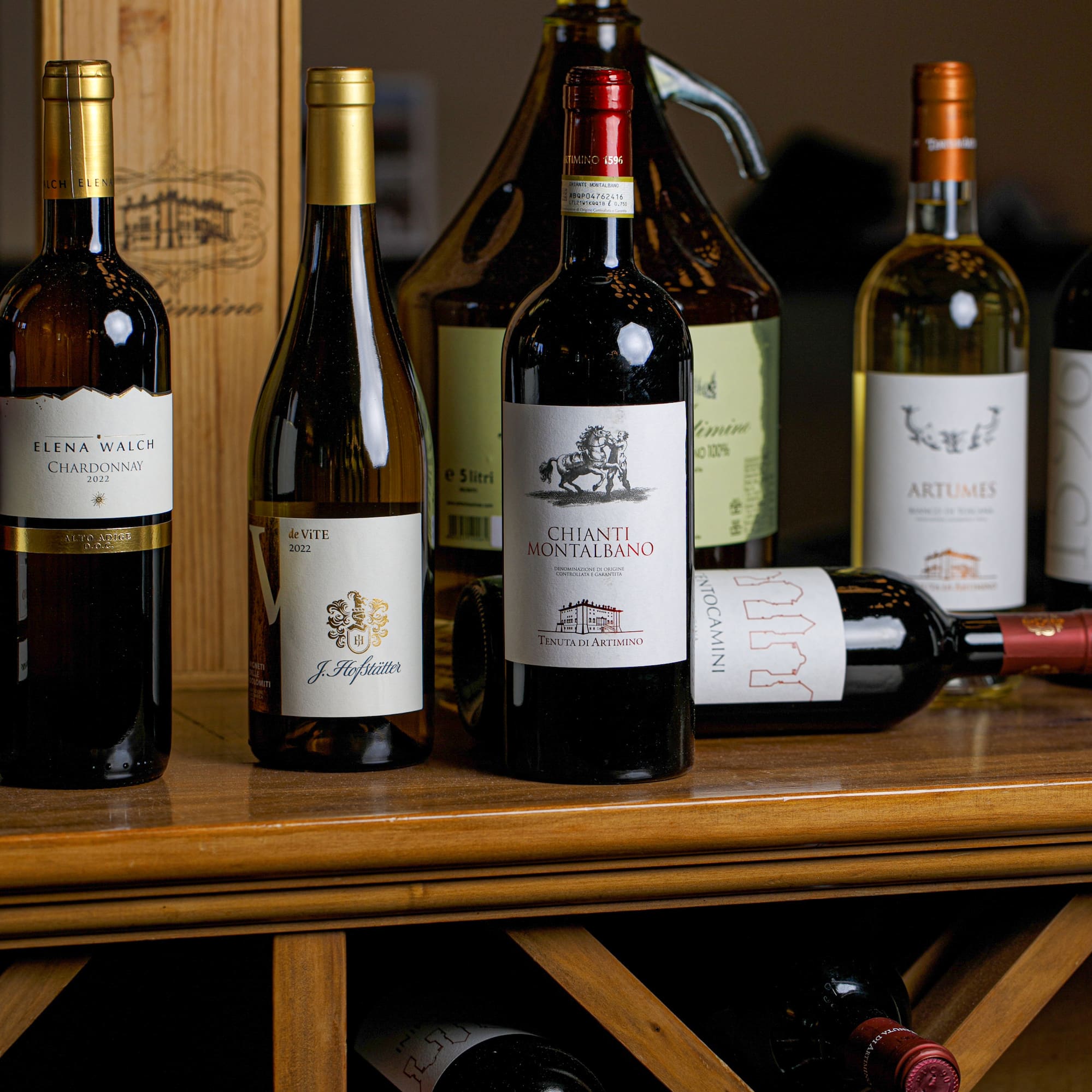 Assorted Italian red and white wines, Chianti, Chardonnay, on a wooden wine rack.
