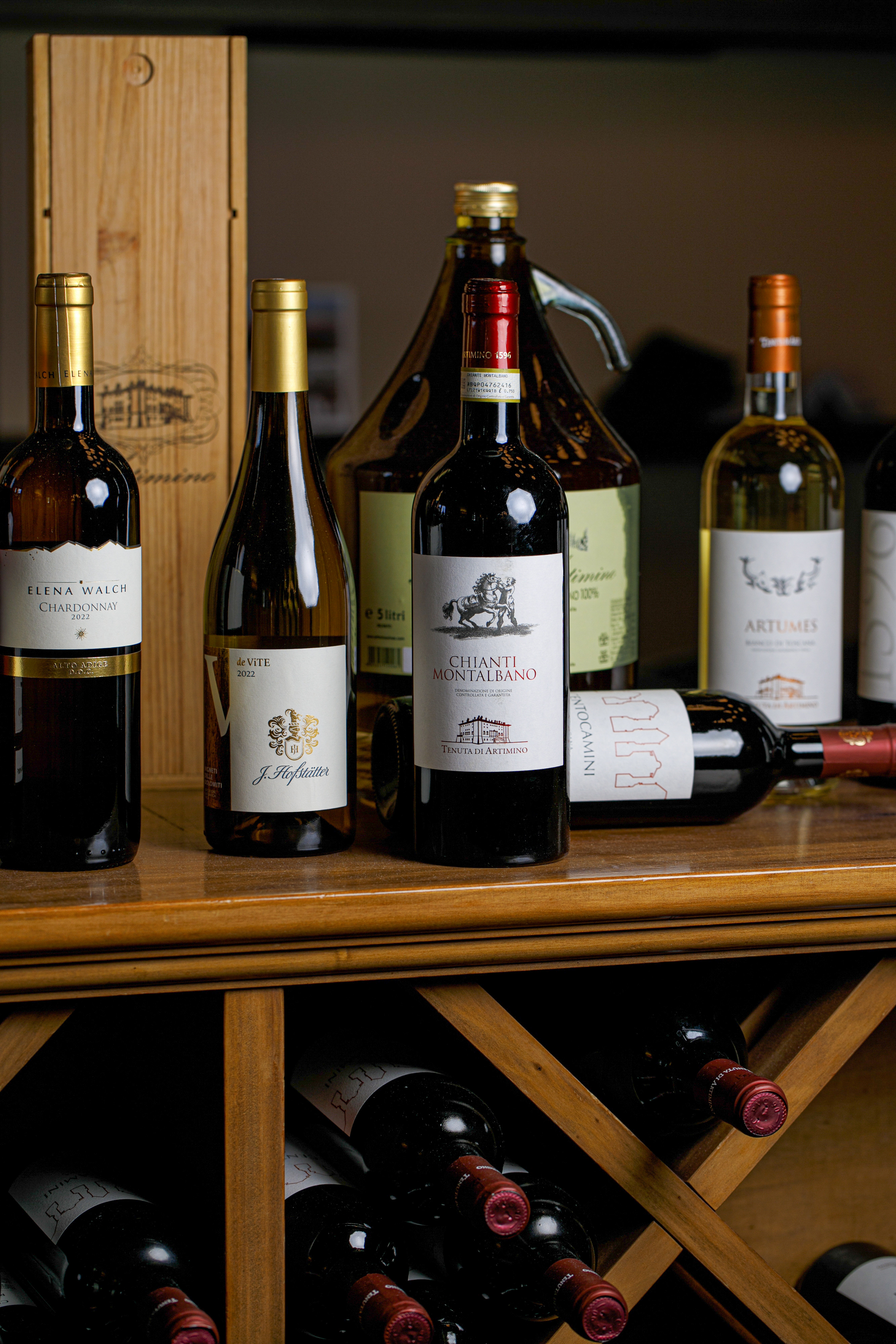 Assorted Italian red and white wines, Chianti, Chardonnay, on a wooden wine rack.