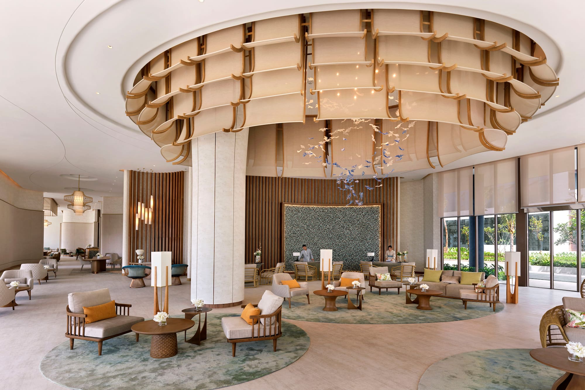 Modern luxury hotel lobby with stylish seating, unique chandelier, and reception.