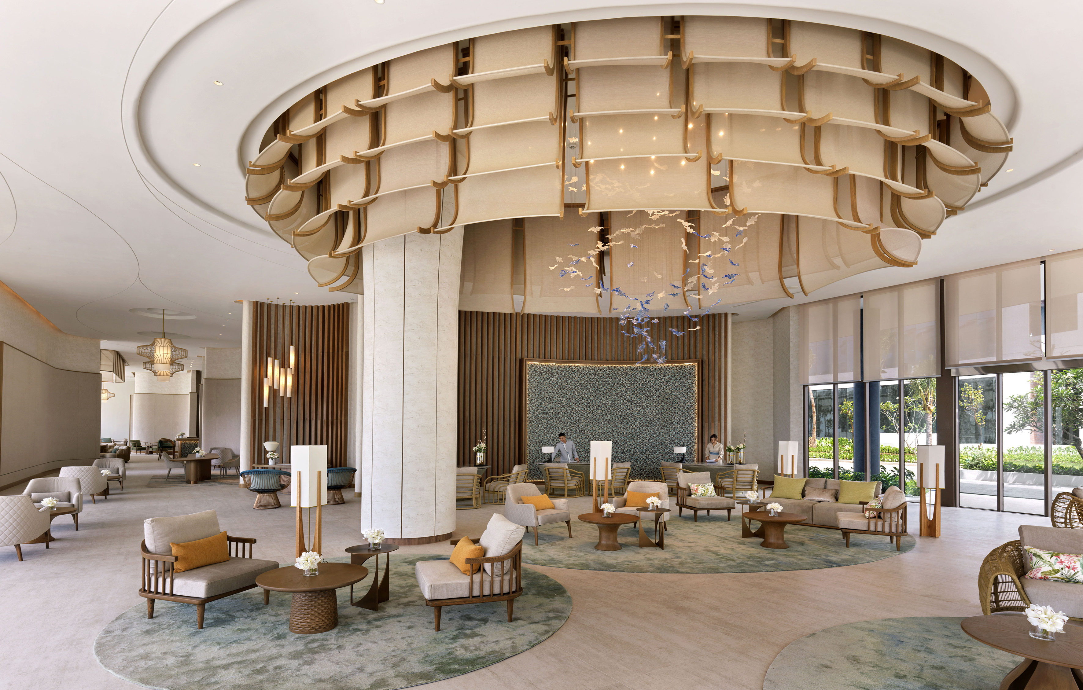 Modern luxury hotel lobby with stylish seating, unique chandelier, and reception.