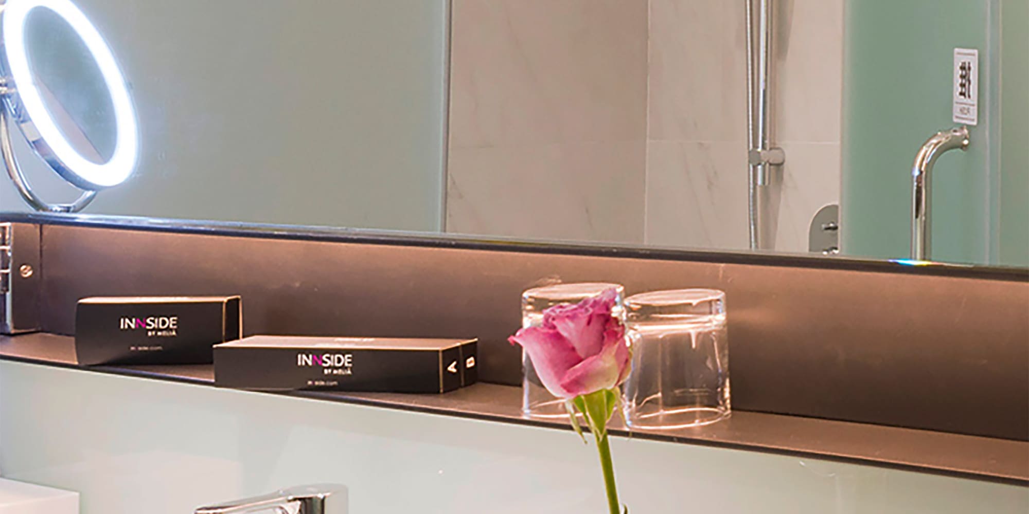 a bathroom with a pink rose in a vase