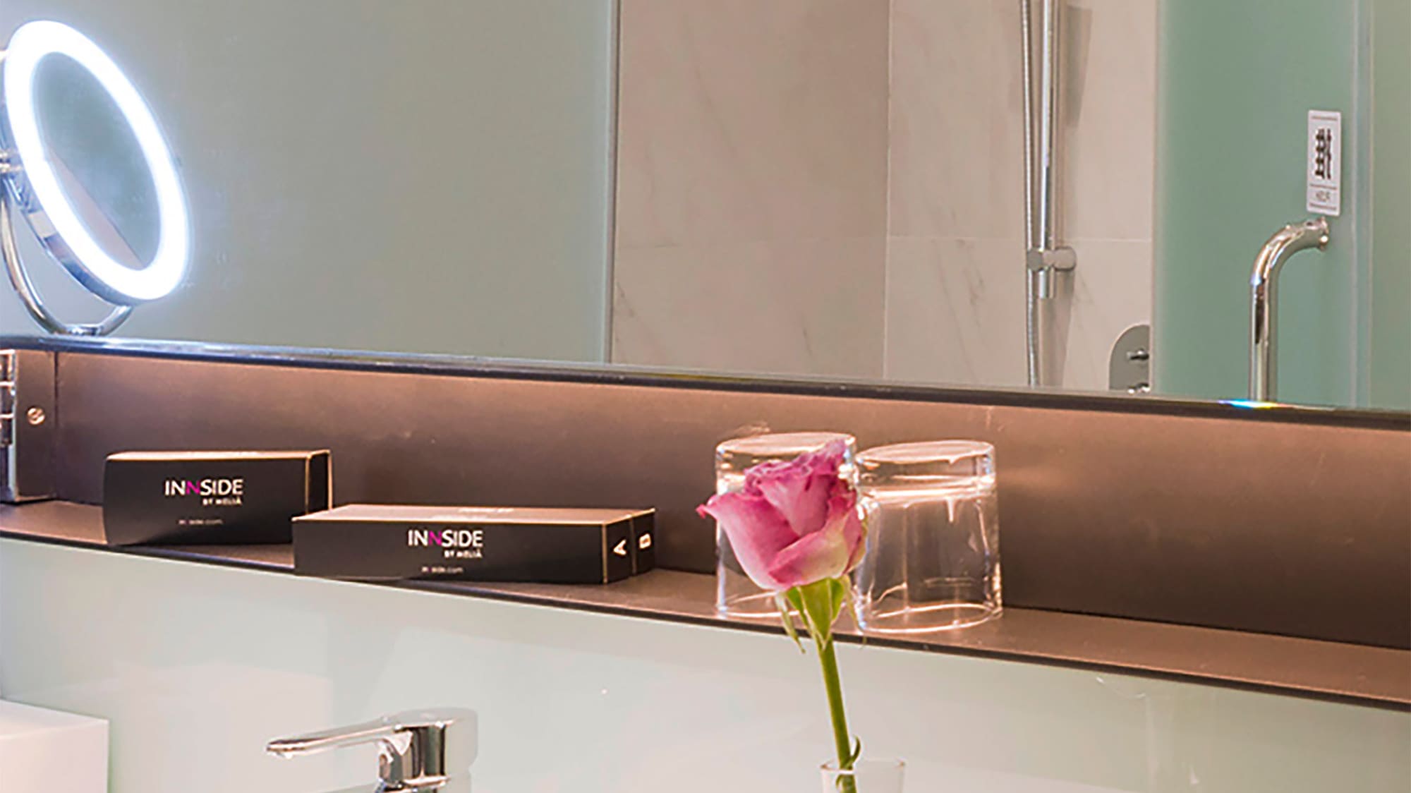 a bathroom with a pink rose in a vase