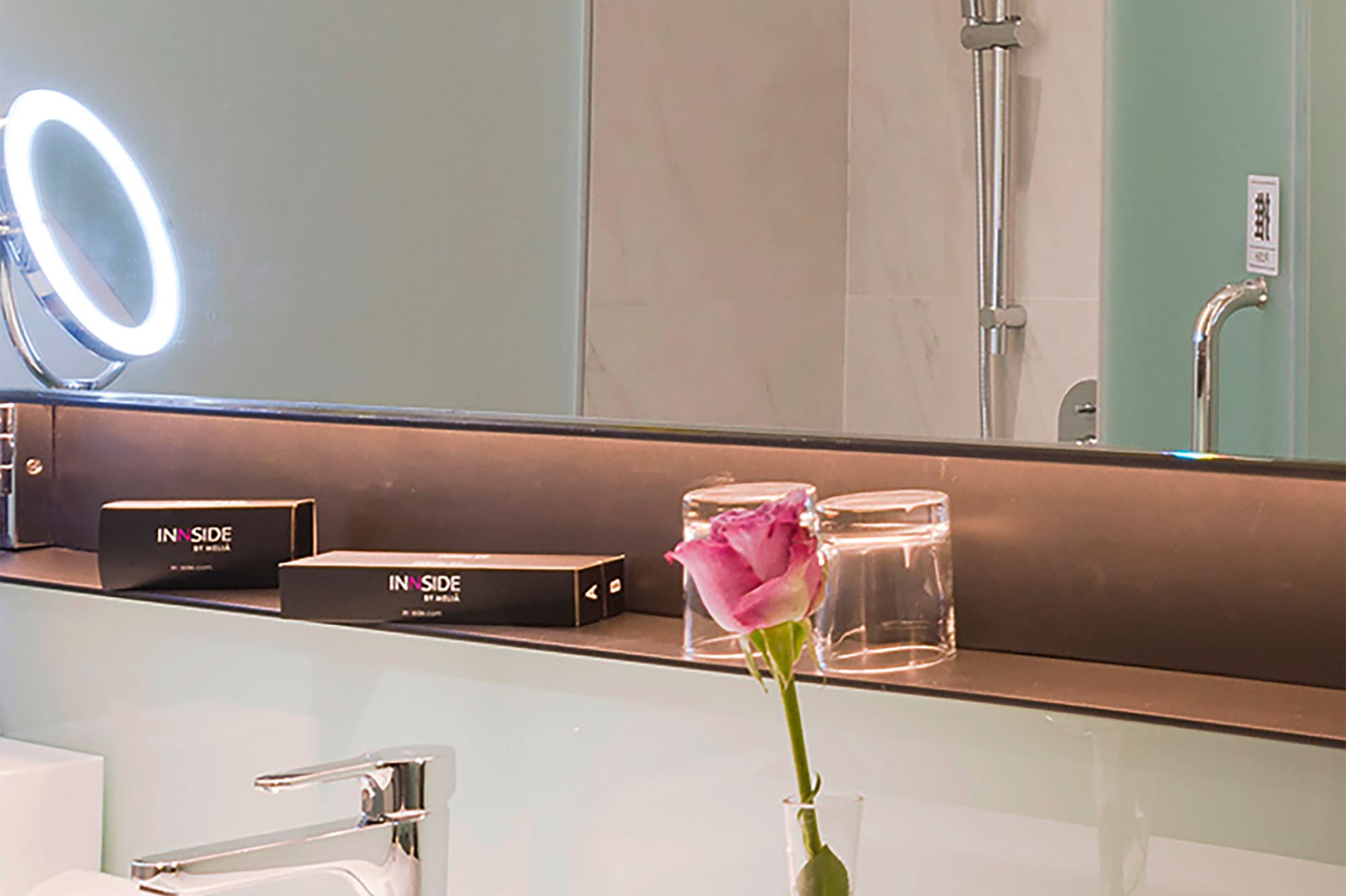a bathroom with a pink rose in a vase