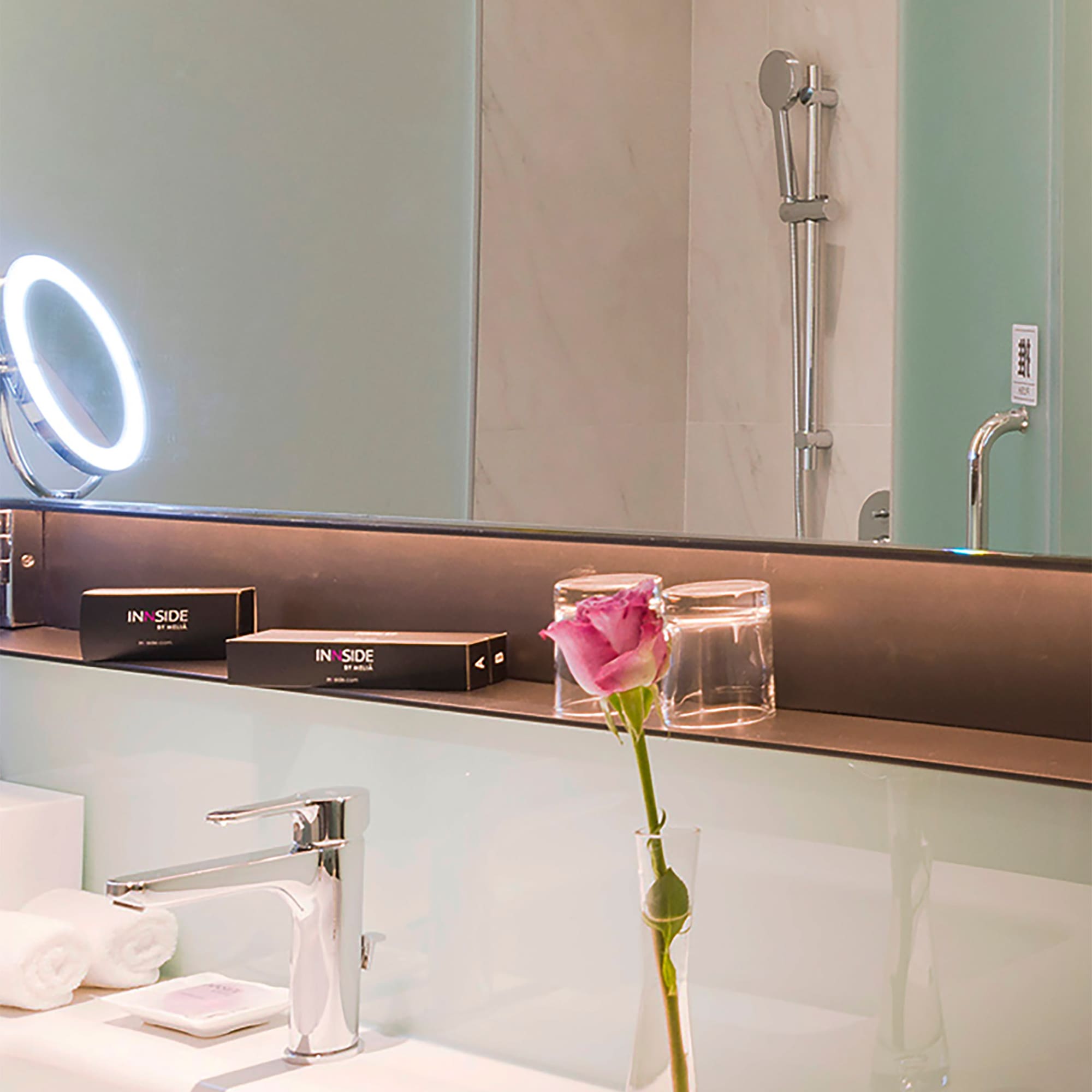 a bathroom with a pink rose in a vase