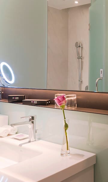 a bathroom with a pink rose in a vase