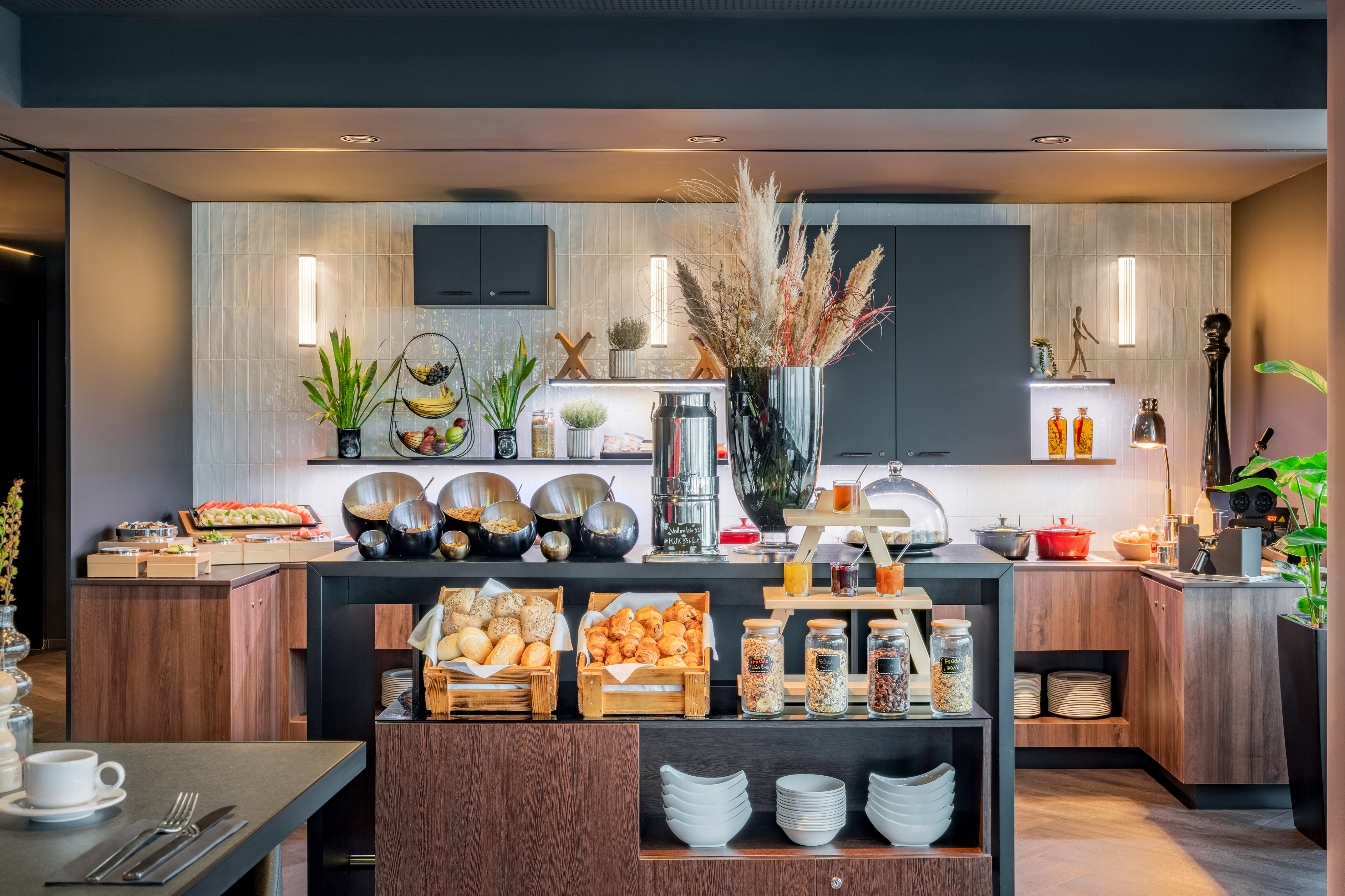 Modern breakfast buffet with fresh pastries, cereals, fruit, and juices.