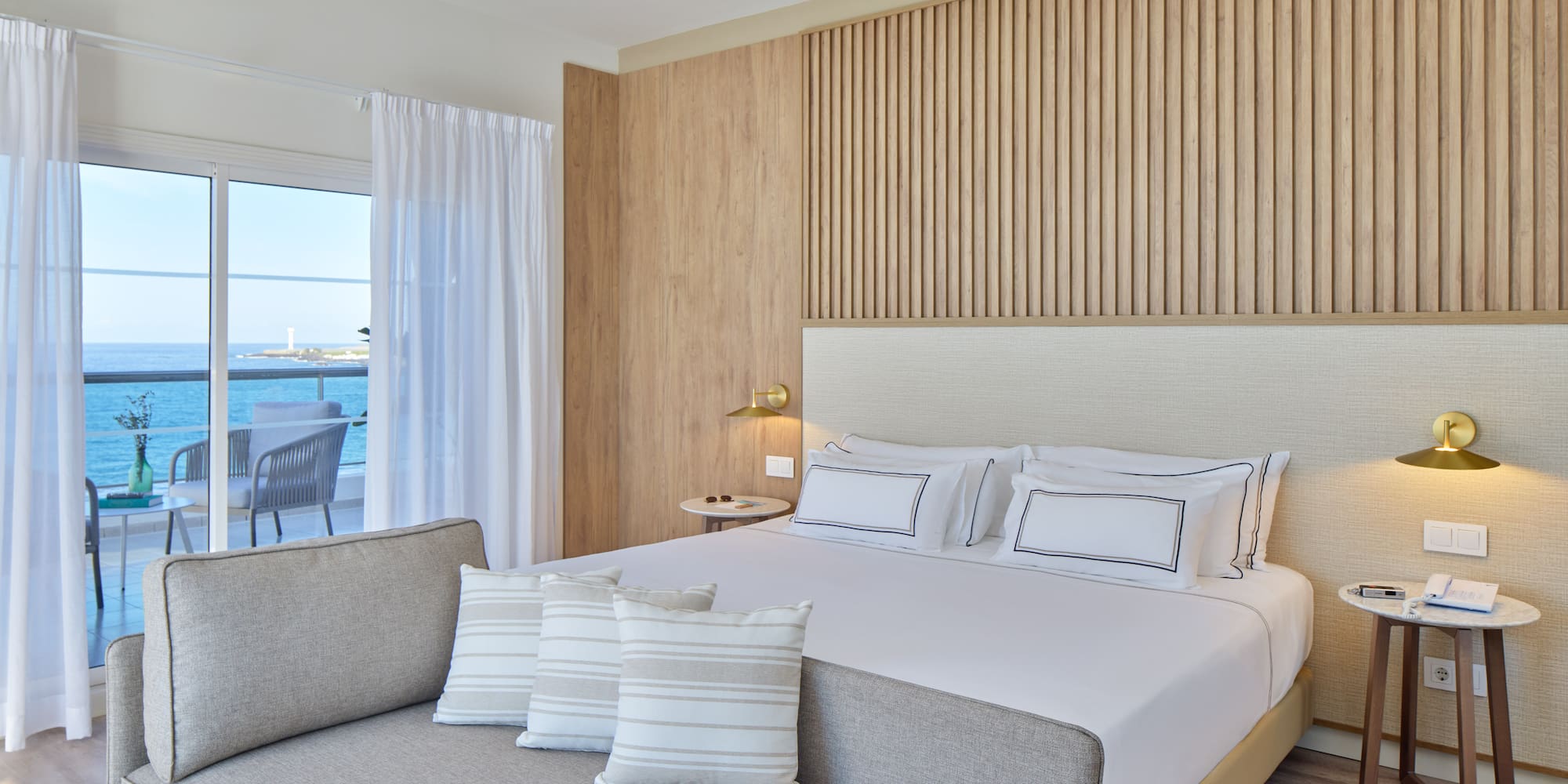 a bed with pillows in a room with a view of the ocean