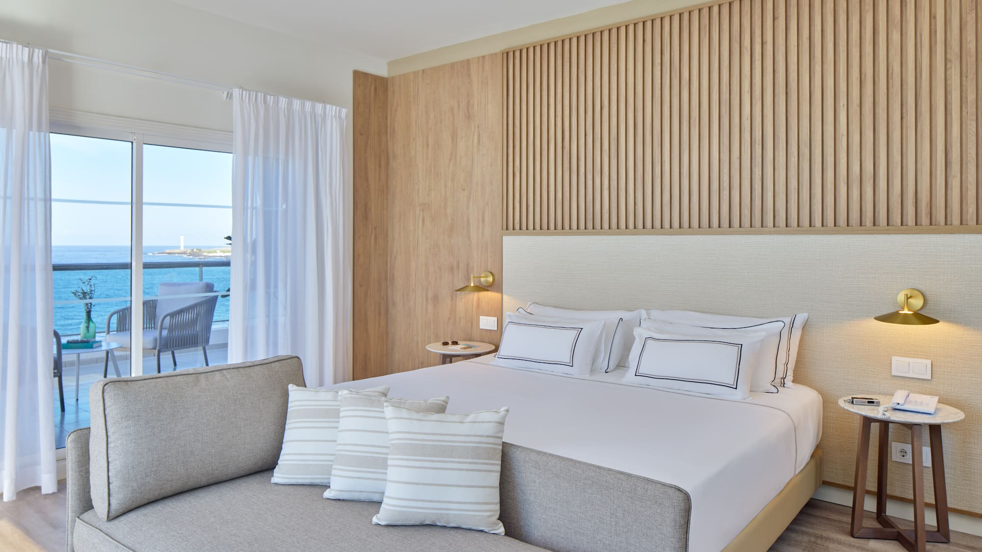 a bed with pillows in a room with a view of the ocean