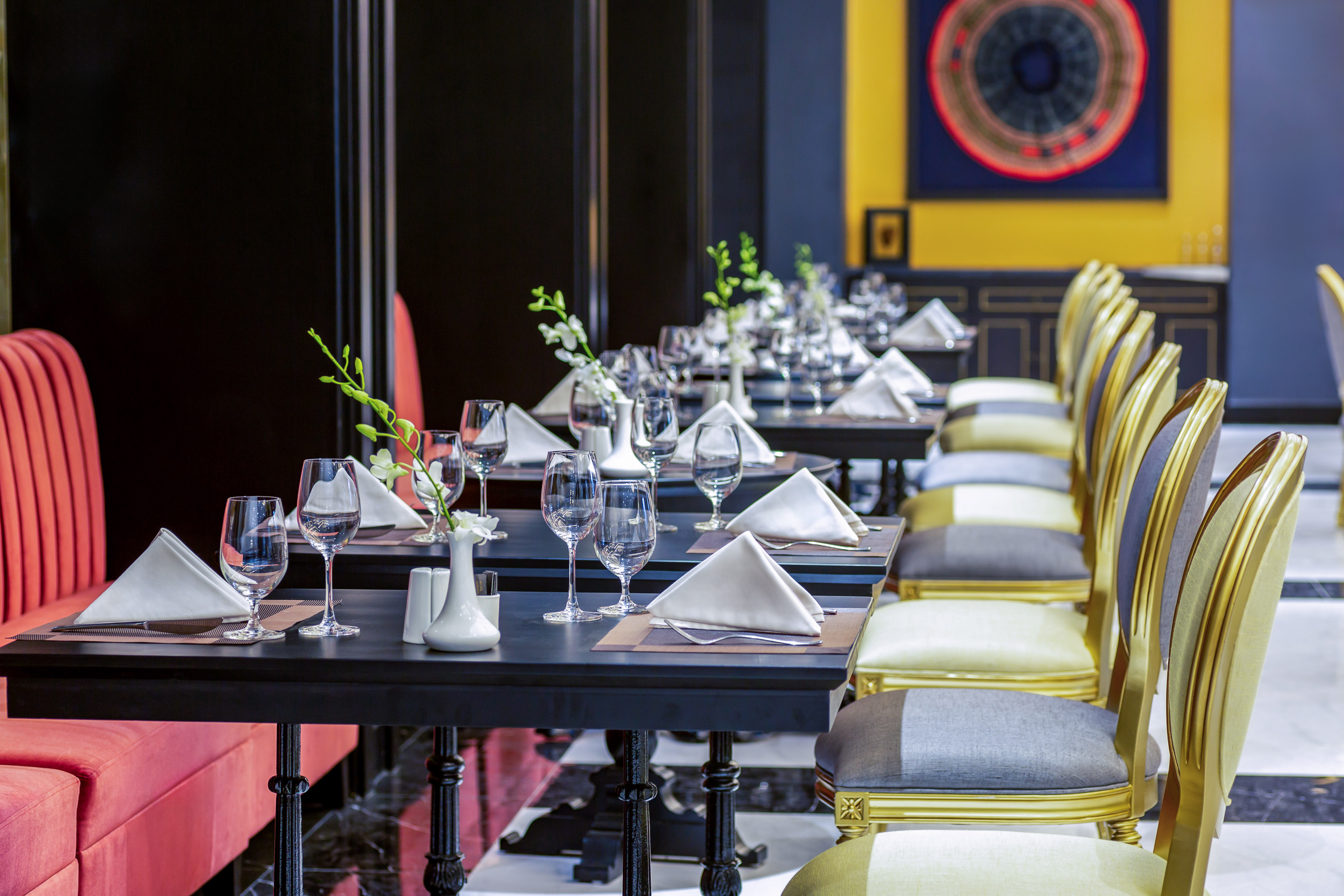 Elegant restaurant dining room with set tables, red booth, and gold chairs. - Restaurante BB, Cocina fusión asiática - Hotel Sapa Square Affiliated by Meliá, Sapa