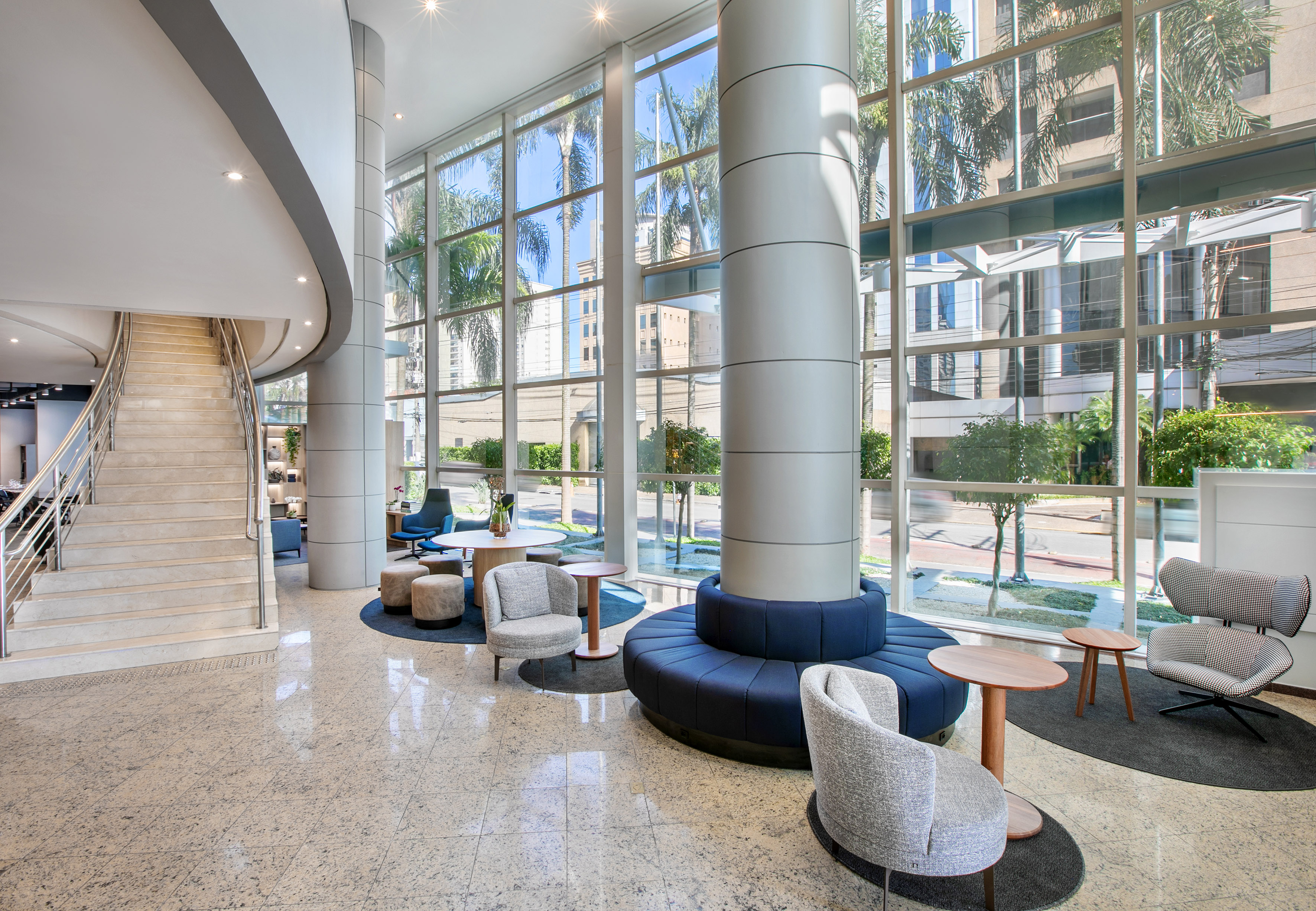 Modern lobby with grand staircase, large windows, and contemporary lounge seating.