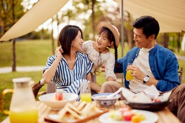 a man and woman with a child at a picnic table