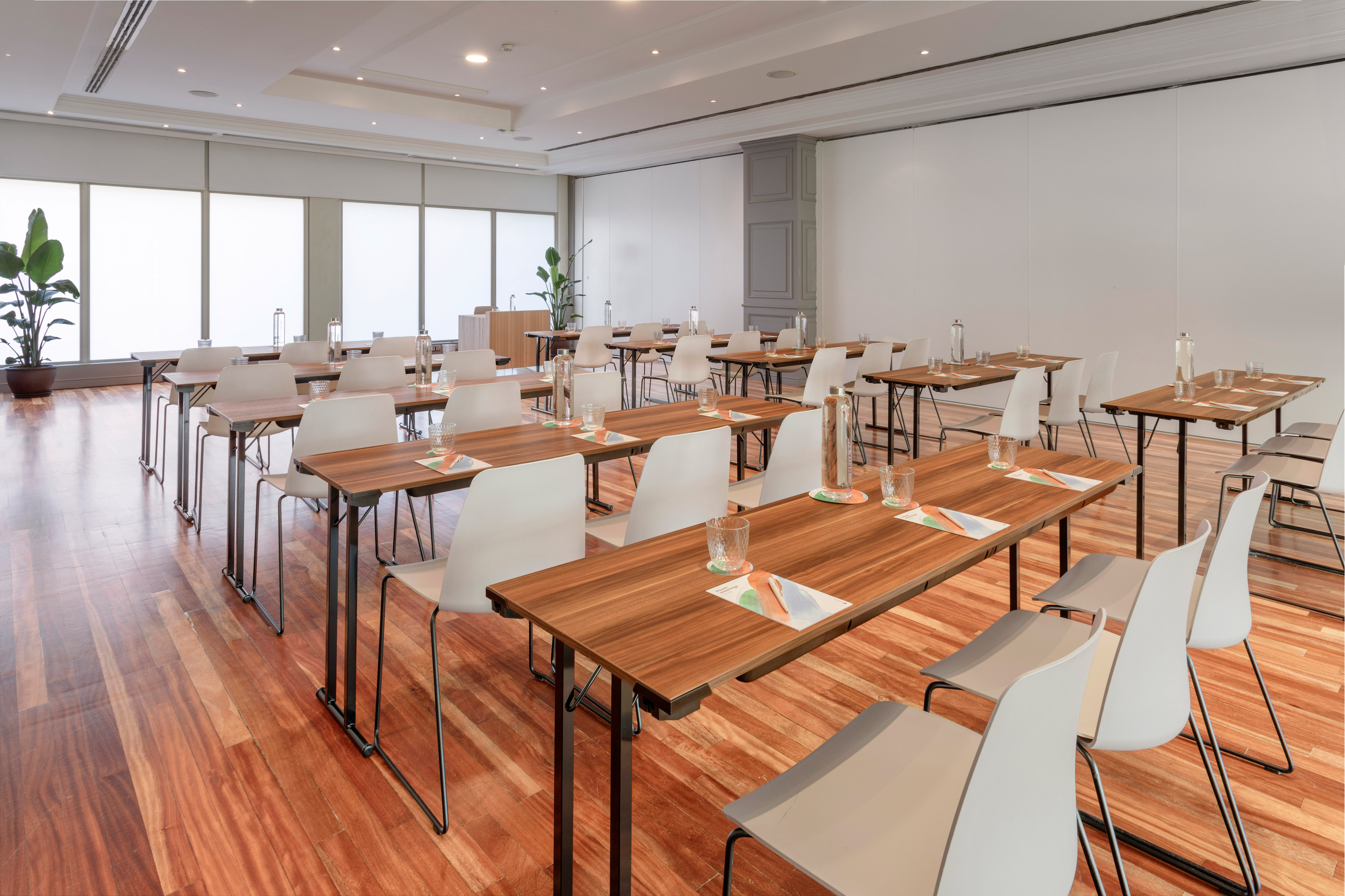 Bright conference room with classroom setup, wooden tables, and white chairs.