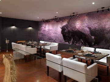 a room with white chairs and tables and a large picture of a buffalo