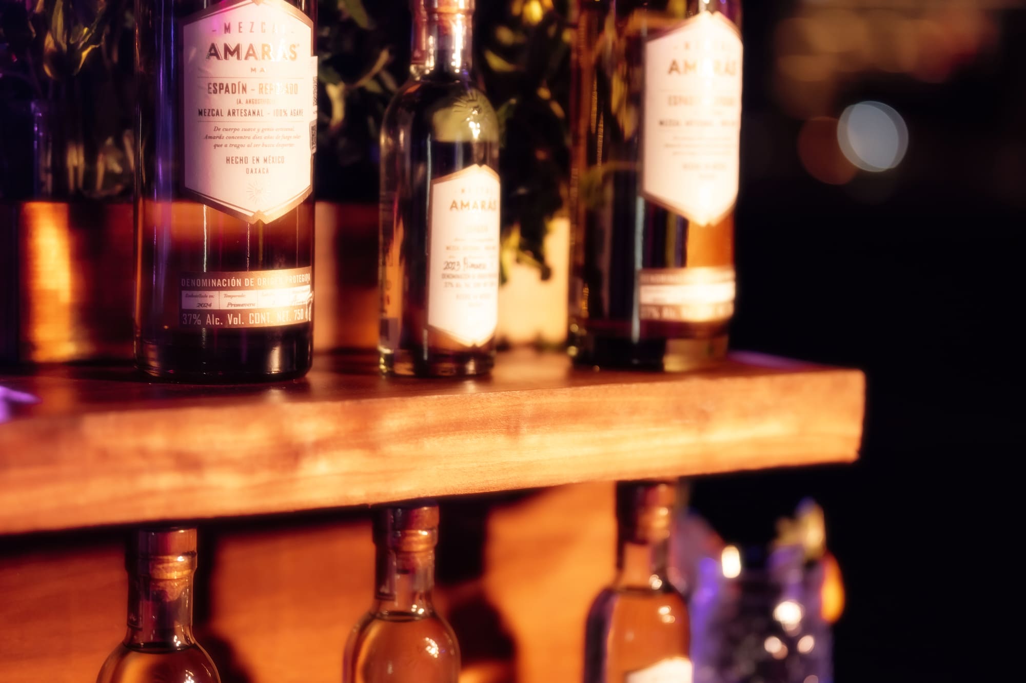 a group of bottles of alcohol on a wooden shelf