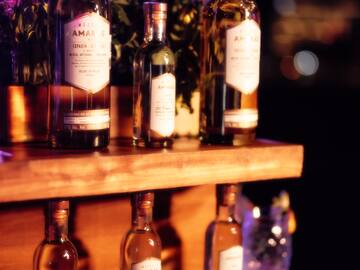 a group of bottles of alcohol on a wooden shelf