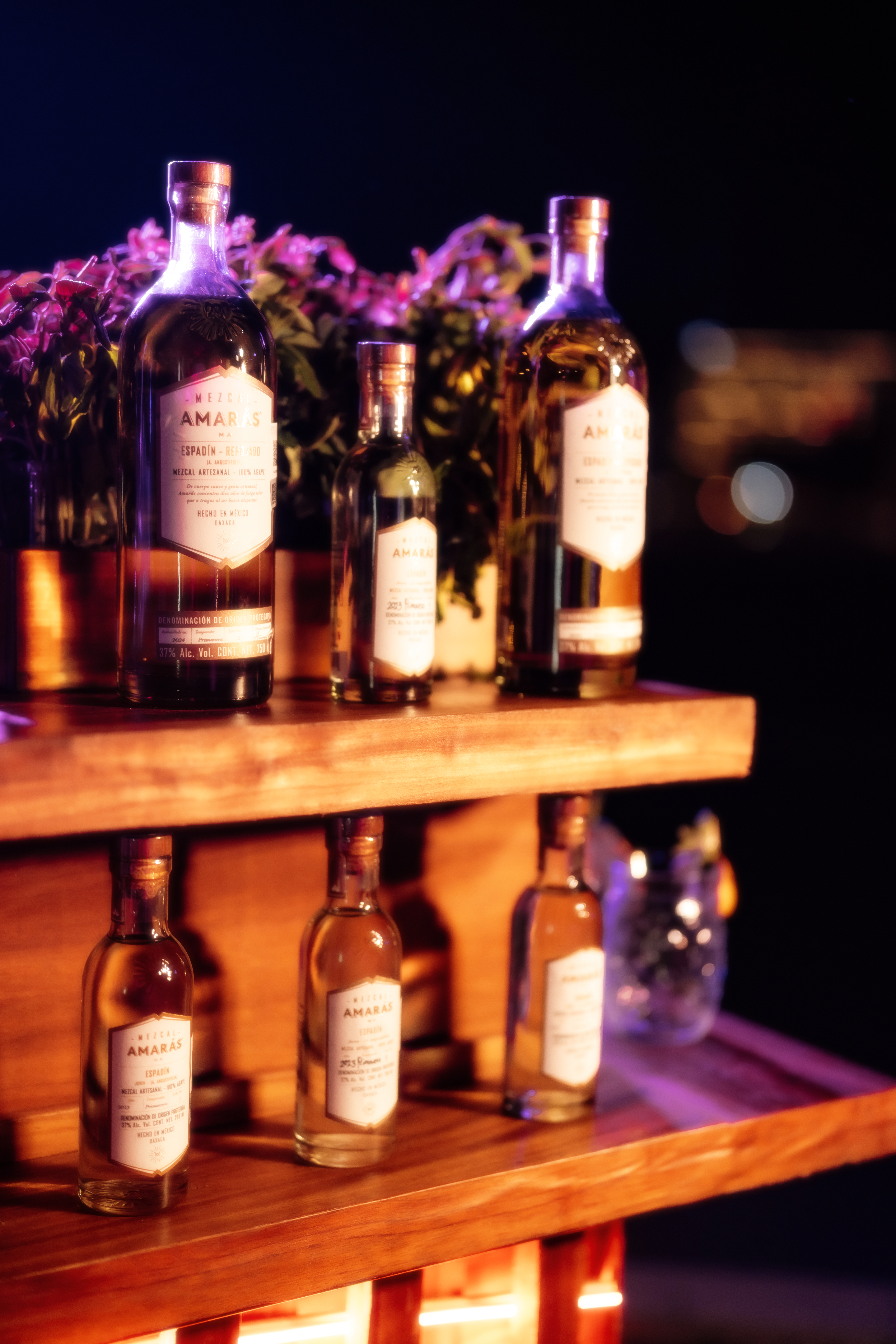 a group of bottles of alcohol on a wooden shelf